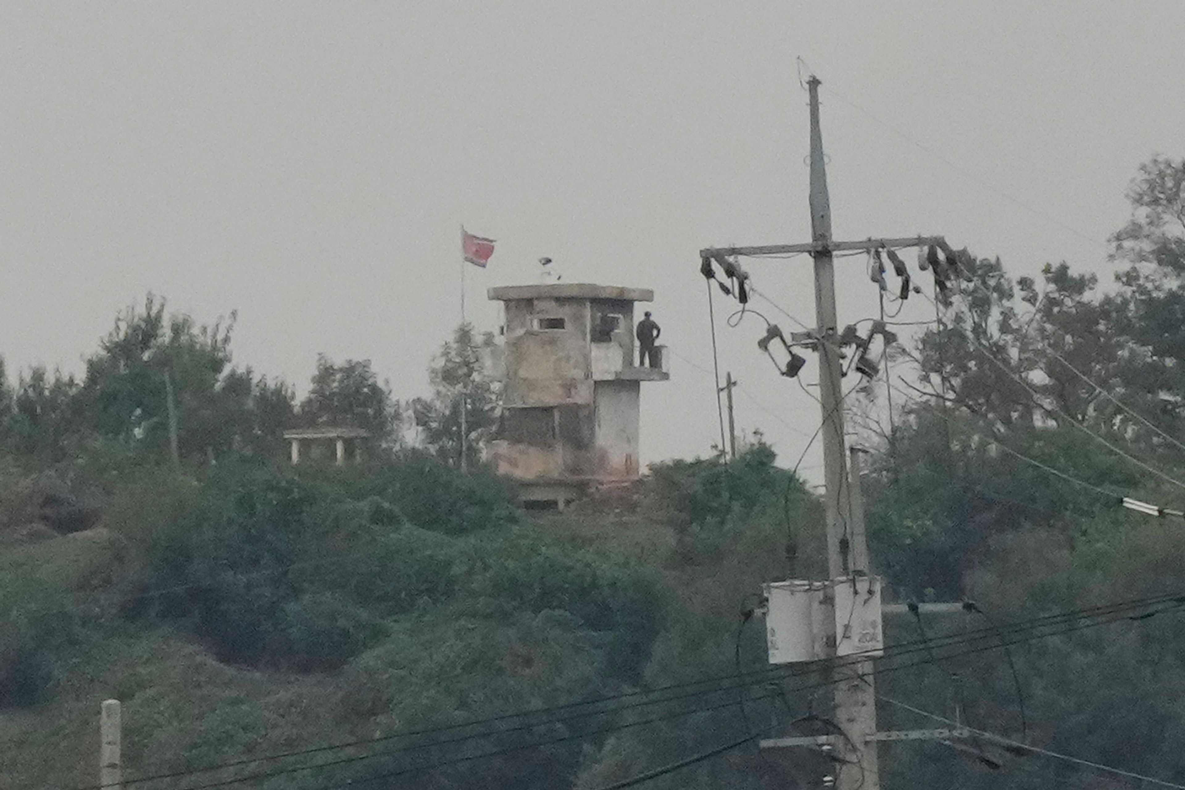 A North Korean soldier stands guard at the North's military guard post as a North Korean flag flutters in the wind, as seen from Paju, South Korea, near the border with North Korea, Monday, Oct. 14, 2024. (AP Photo/Ahn Young-joon)