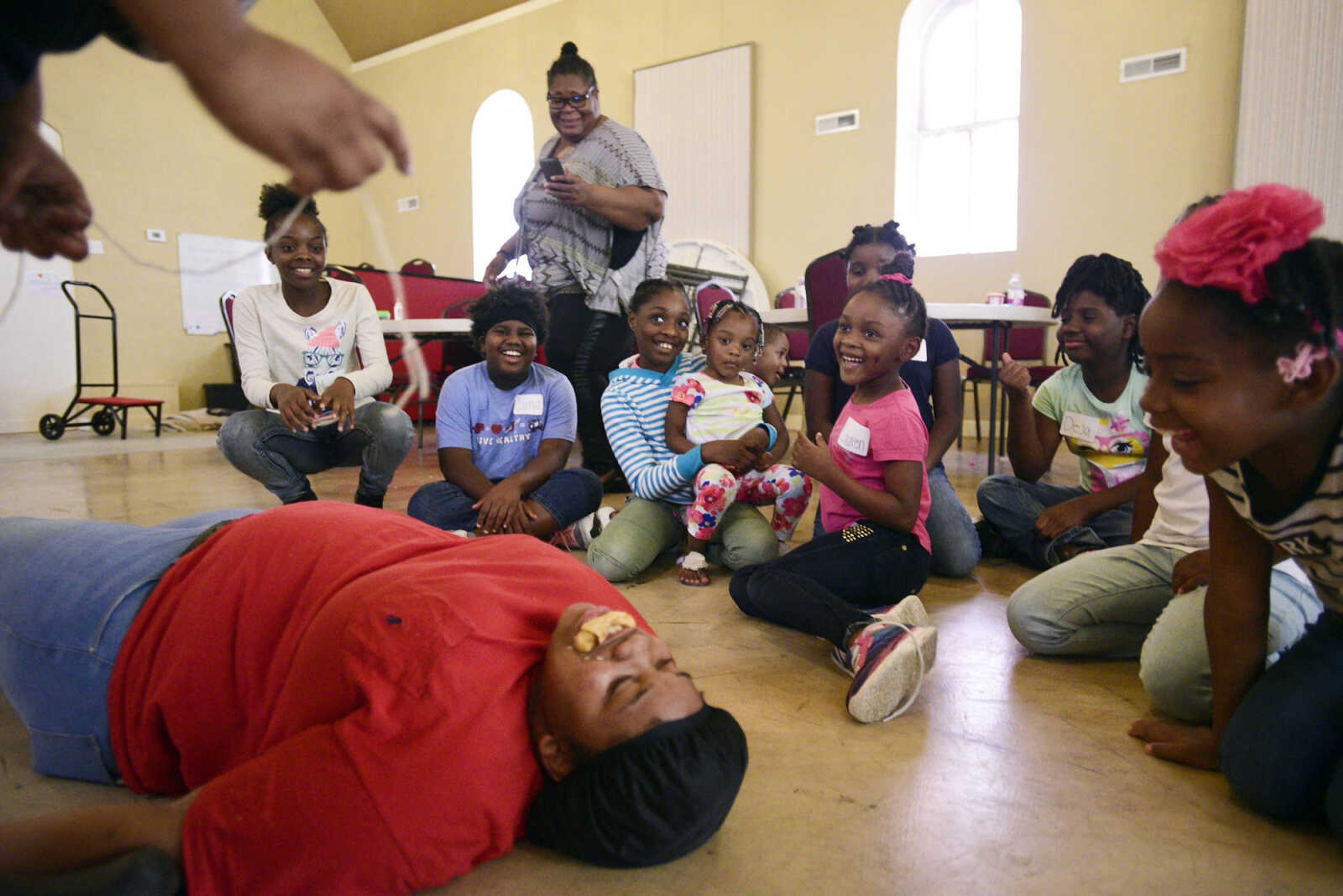 Students giggle as Cherish Moore feeds her sister Chamika a donut by dangling it from a string on Monday, Aug. 14, 2017, during the Salvation Army's after school program at The Bridge Outreach Center in Cape Girardeau.