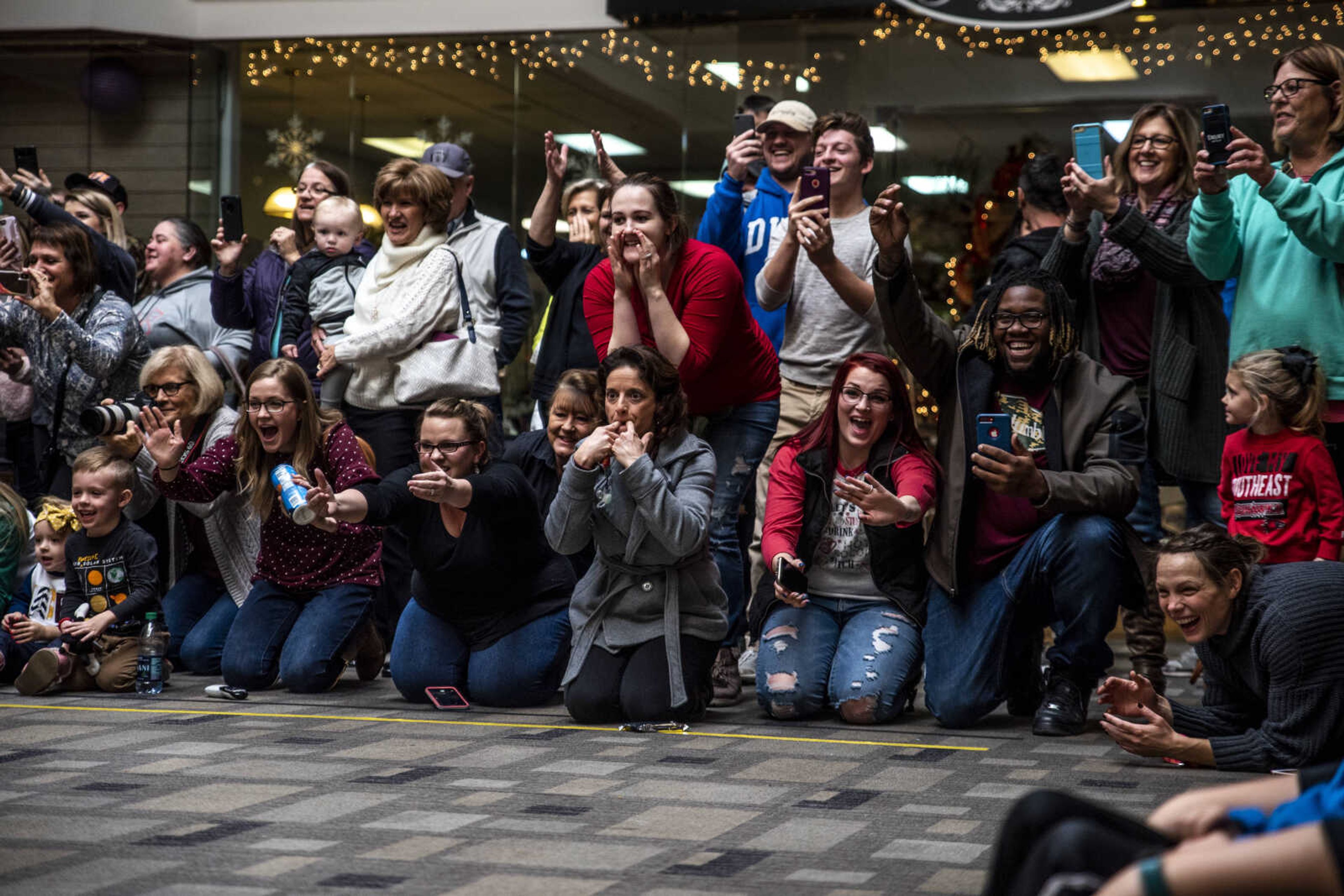 Parents and family members cheer for their baby to crawl toward them during the first heat of the Elf Races at West Park Mall Sunday, Dec. 9, 2018, in Cape Girardeau.