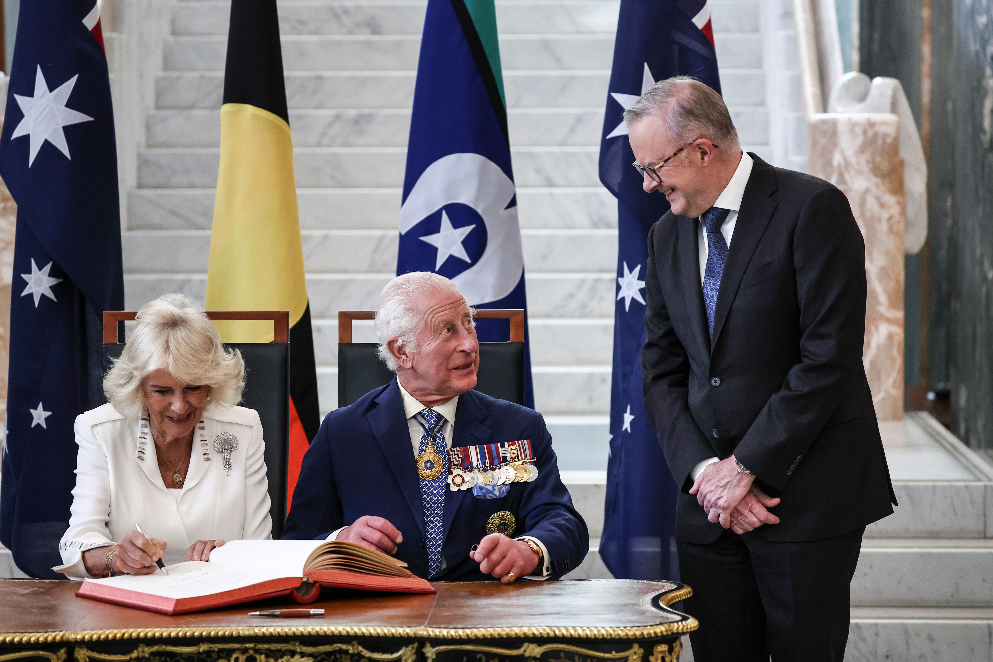 Britain's King Charles III, center, talks to Australia's Prime Minister Anthony Albanese as he and Queen Camilla sign a visitors' book in the Marble Foyer of Parliament House in Canberra, Australia, Monday, Oct. 21, 2024. (David Gray/Pool Photo via AP)