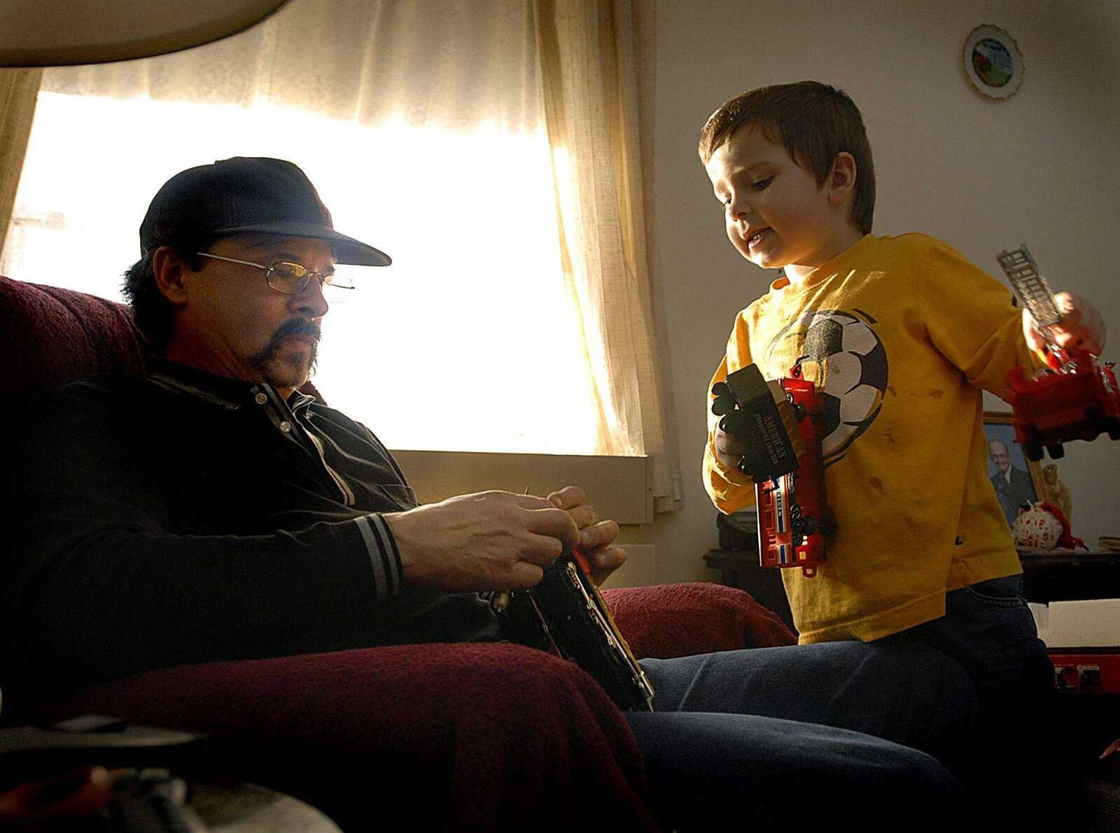 J.T. Niccum, 5, watched as his father Jeff Niccum tried to get his birthday gift, a toy train, running for him Wednesday at Jeff's mother's apartment in Perryville, Mo. (Aaron Eisenhauer)