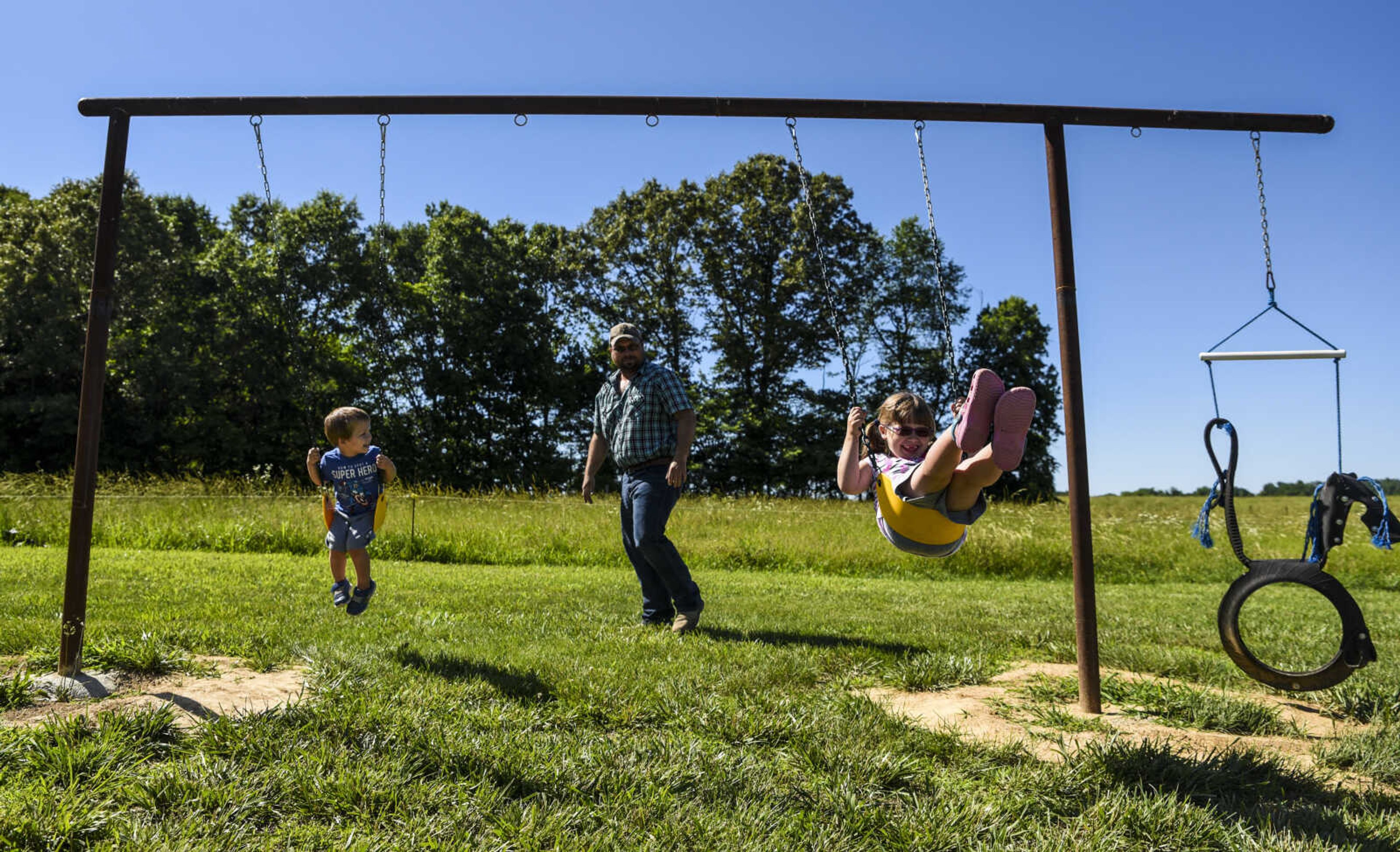 Lindyn Davenport, right, 6, swings with her little brother William Davenport, 3, while their father Derek Davenport watches in their backyard Sunday, June 3, 2018 in Sedgewickville.