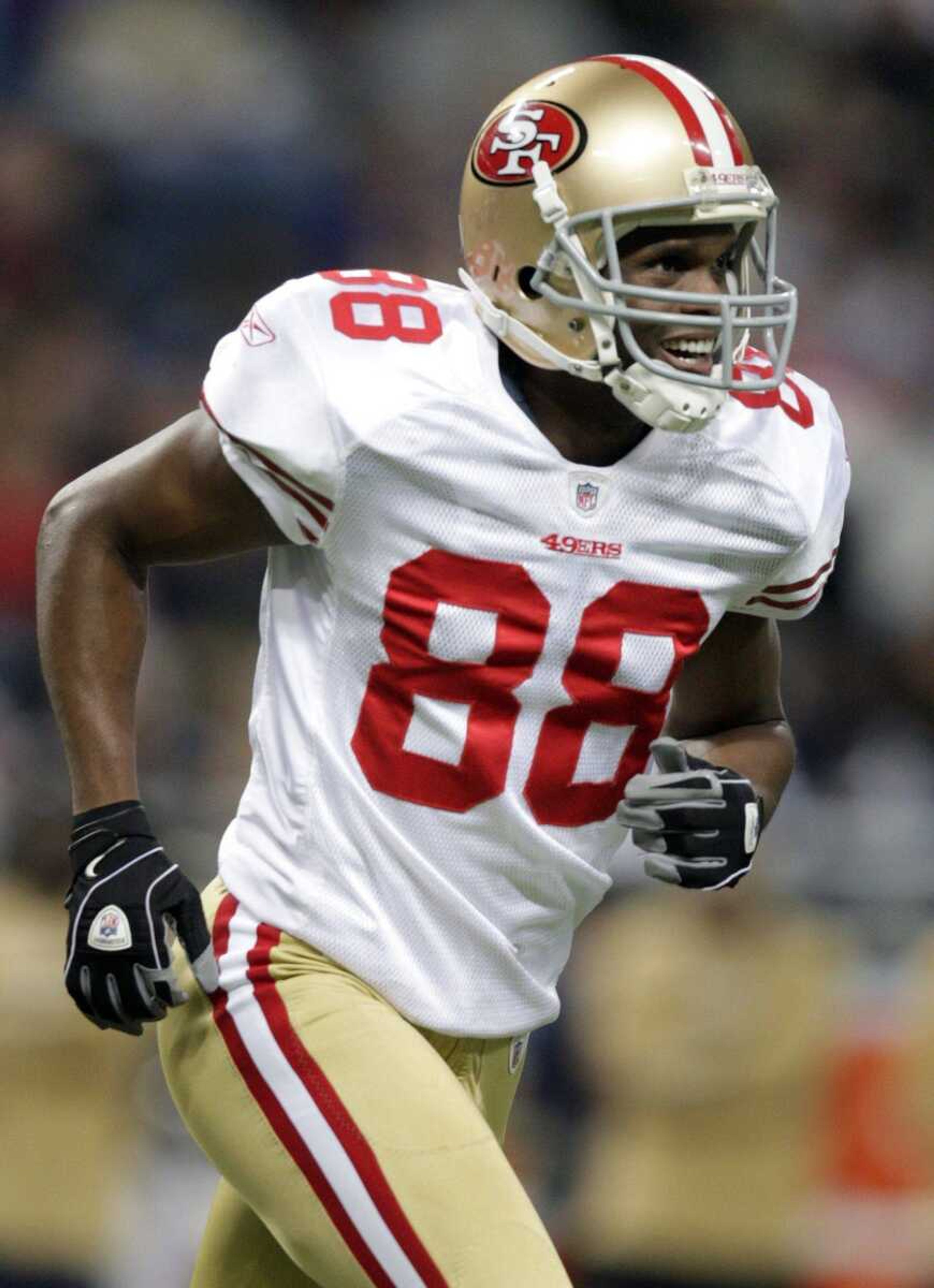 San Francisco 49ers wide receiver Isaac Bruce smiles as he jogs off the field after taking part in the first play during the first quarter of an NFL football game against the St. Louis Rams, Sunday, Jan. 3, 2010, in St. Louis. (AP Photo/Jeff Roberson)