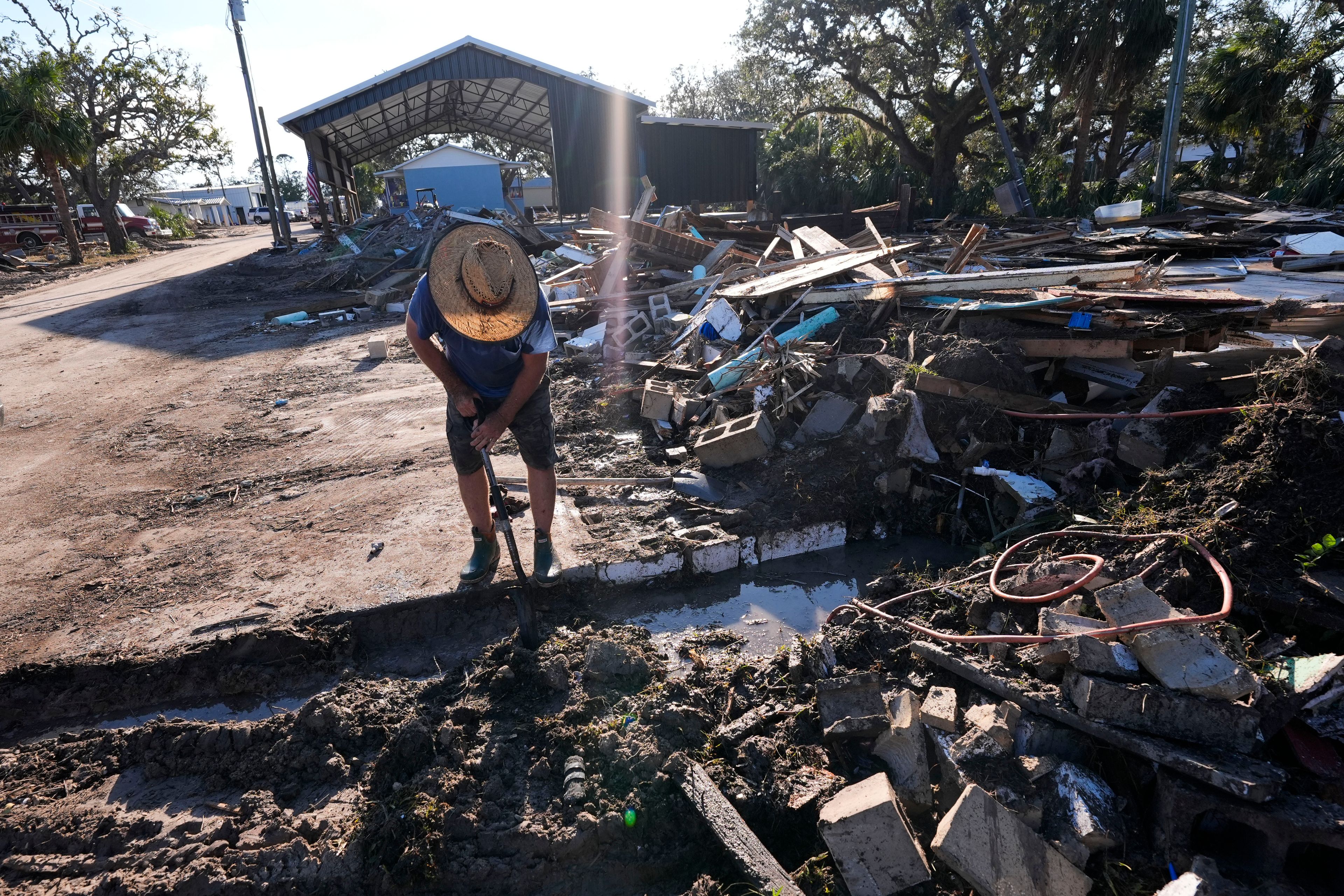 Chris Jordan, maintenance manager for Horseshoe Beach, tries to find a water shutoff valve amid the rubble of the destroyed city hall in the aftermath of Hurricane Helene, in Horseshoe Beach, Fla., Sunday, Sept. 29, 2024. (AP Photo/Gerald Herbert)