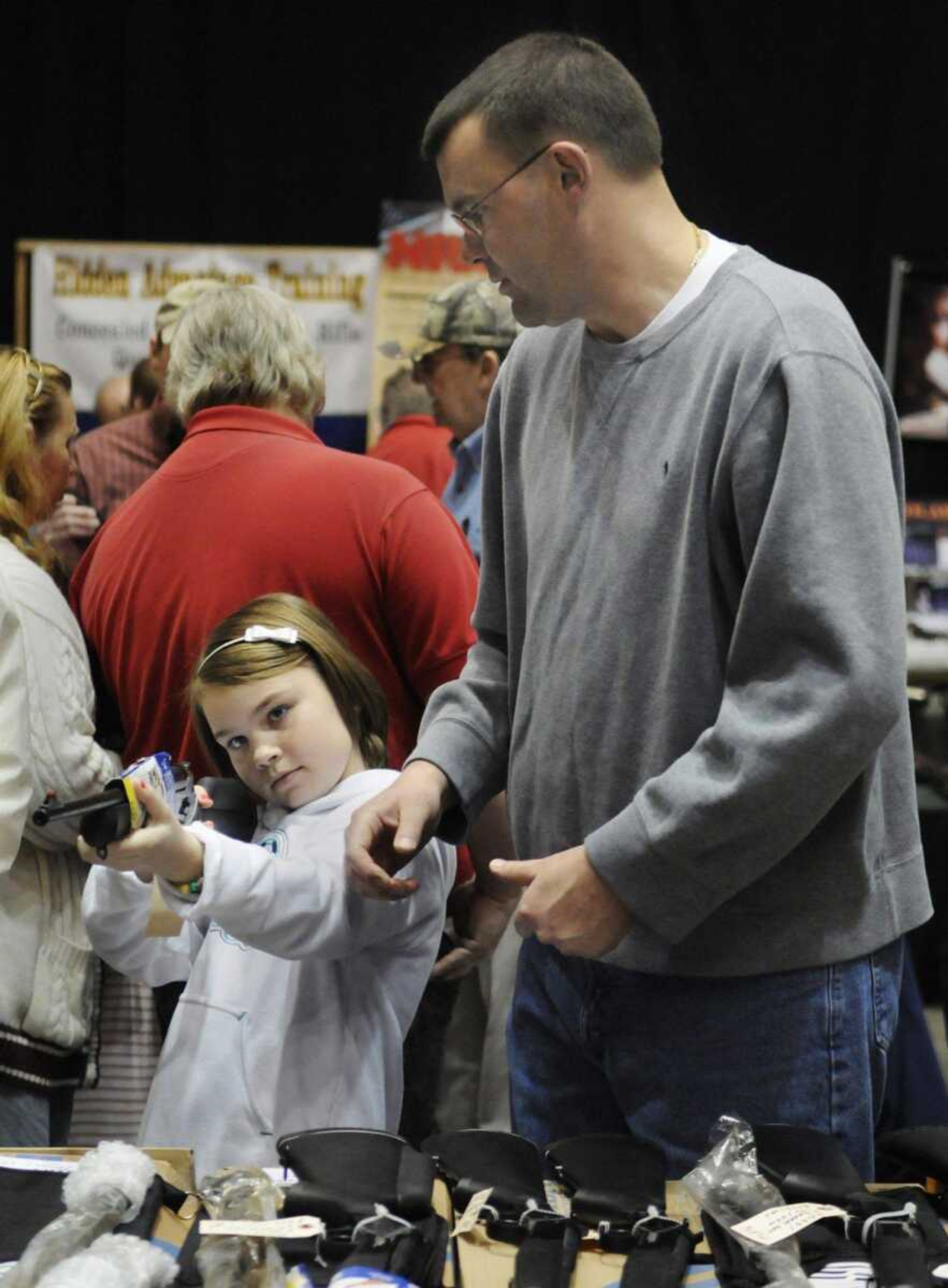 Cape Girardeau resident Todd Alexander, right, helps daughter Payton Alexander, 9, look at a Rossi Youth Model Shotgun/Rifle Combo during the Missouri Gun and Knife Show at the Show Me Center on Saturday, March 13, 2010. Payton started hunting last year and came to the show with her father to look for her first gun. (KRISTIN EBERTS)