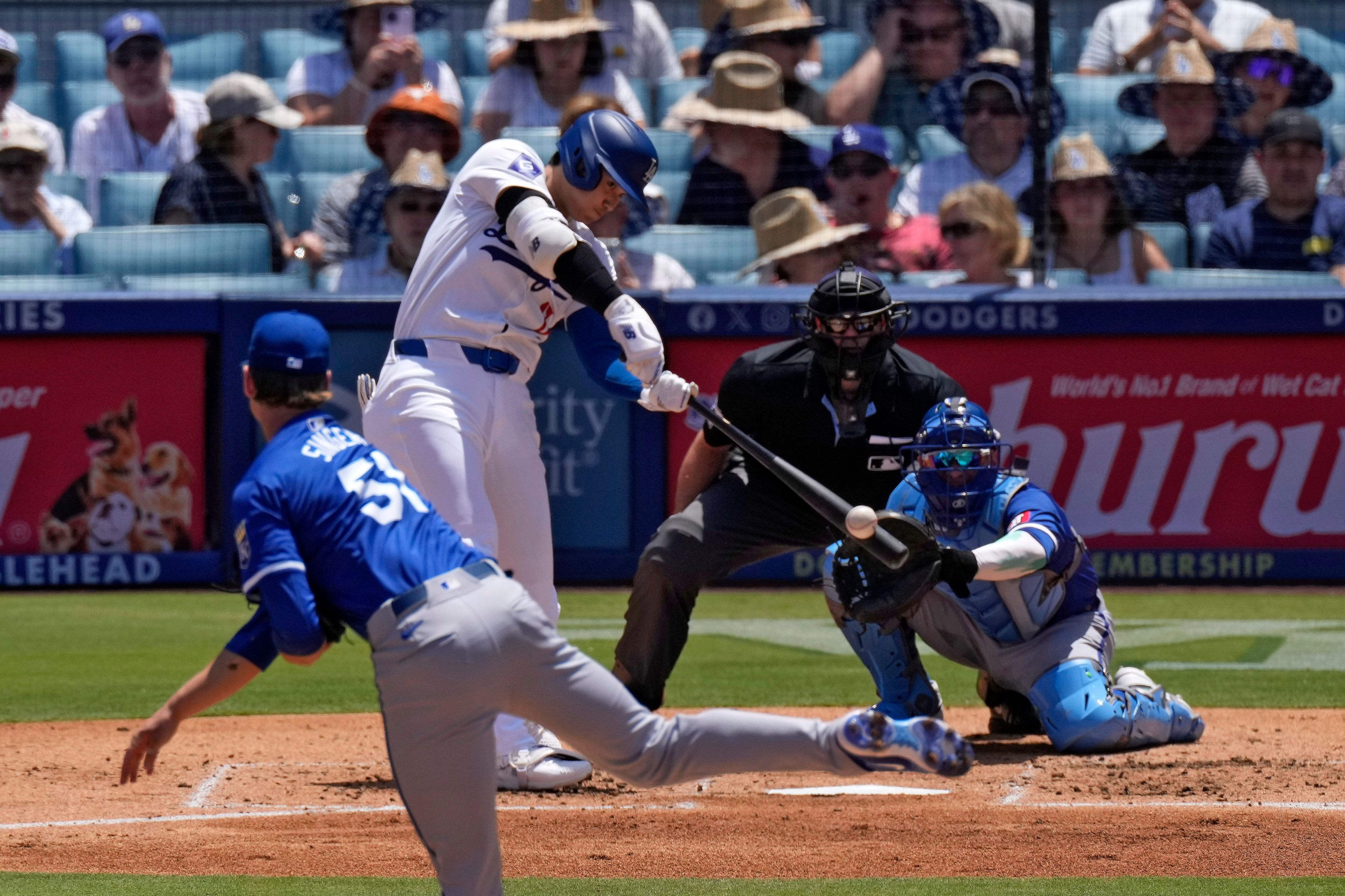 Los Angeles Dodgers' Shohei Ohtani, second from left, hits a solo home run as Kansas City Royals starting pitcher Brady Singer, left, and catcher Freddy Fermin, right, watch along with home plate umpire Ryan Additon during the third inning of a baseball game Sunday, June 16, 2024, in Los Angeles. (AP Photo/Mark J. Terrill)