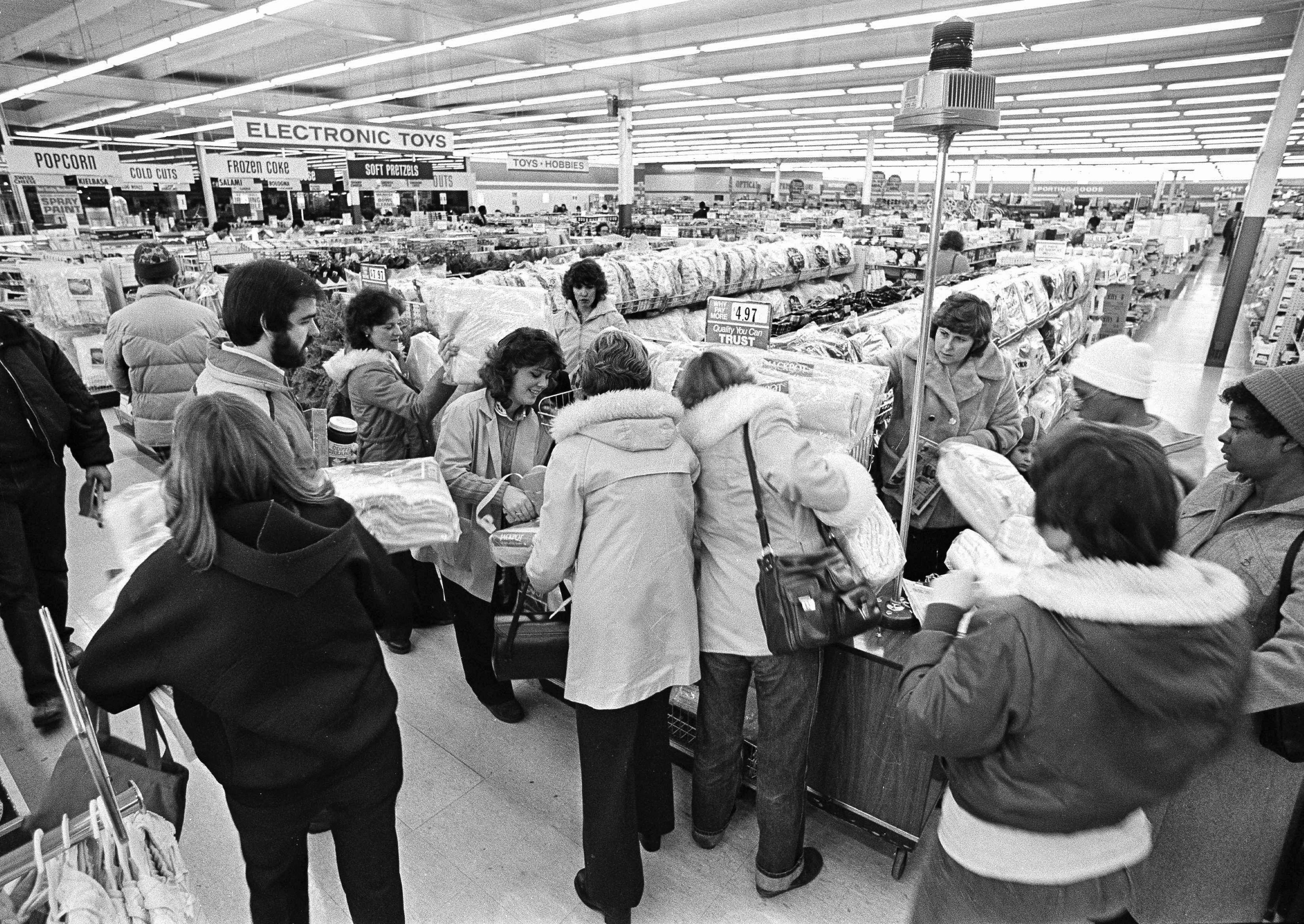 FILE - Kmart shoppers mill around the flashing blue light, sign of the "Blue Light Special," at the first Kmart ever built in Garden City, Mich., on March 1, 1982. (AP Photo/Dale Young, File)