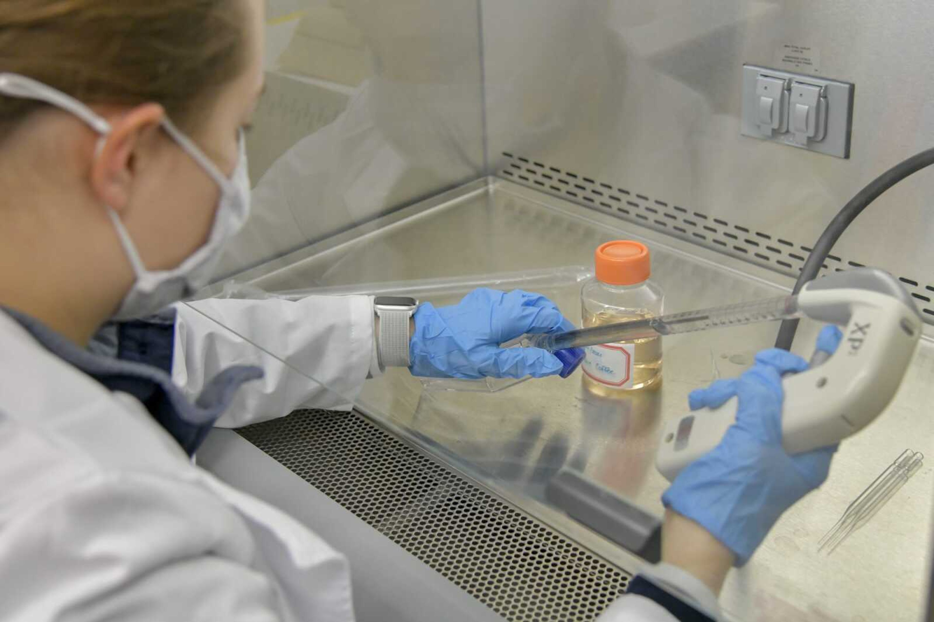 Mallorie Coffee injects new media that she created, from the orange lid container, into a container containing human cells to test her chemical-based treatment for strep-throat in a sanitized fume hood at a Southeast Missouri State University lab in Cape Girardeau on Feb. 25, 2021.