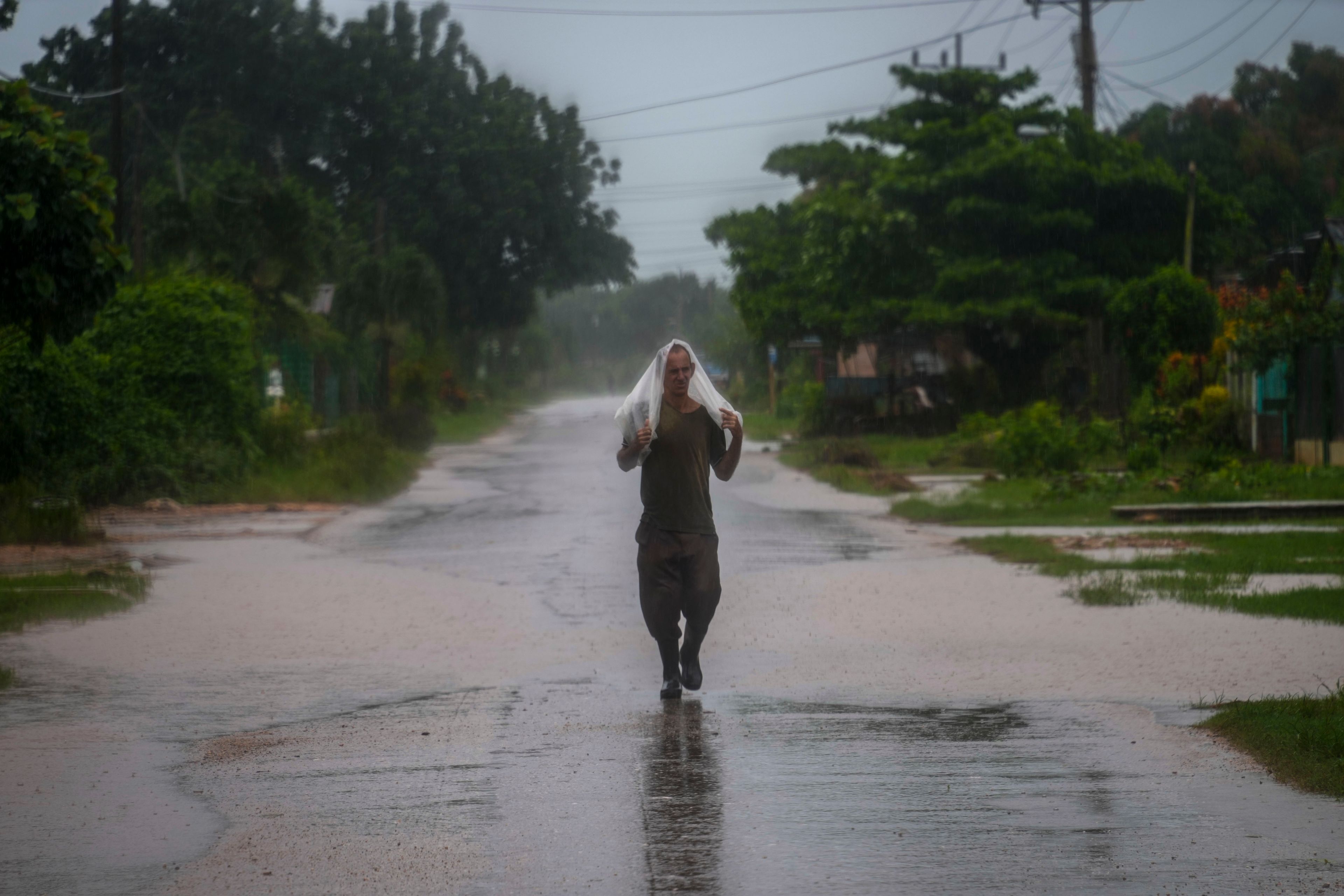 A resident uses a piece of plastic as protection from heavy rains brought on by Hurricane Helene, in Batabano, Cuba, Wednesday, Sept. 25, 2024. (AP Photo/Ramon Espinosa)