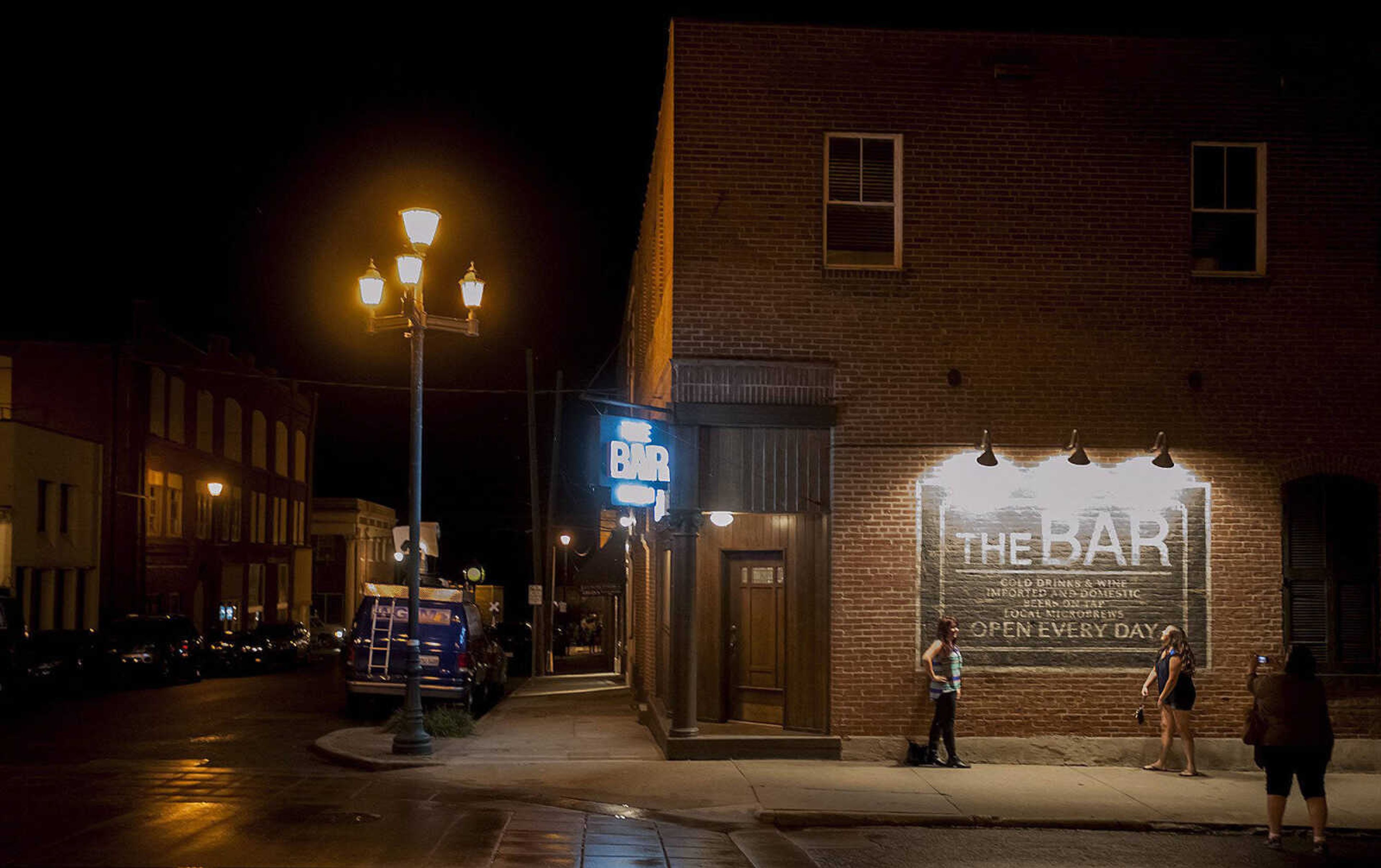 Spectators have their photo taken in front of The Bar, one of the sets for the 20th Century Fox feature film "Gone Girl" in downtown Cape Girardeau. (Southeast Missourian file)