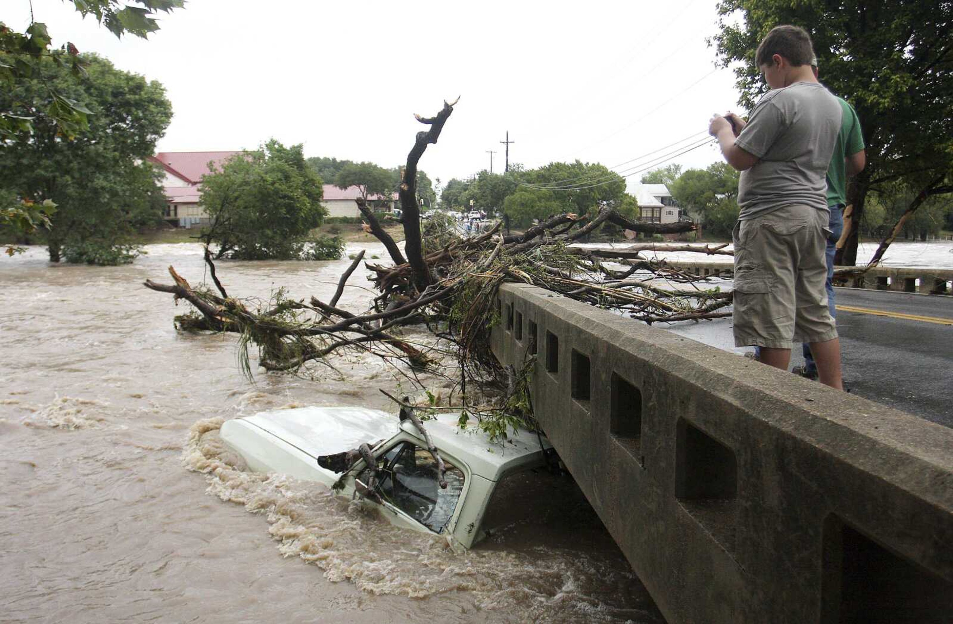 Visitors of Salado, Texas, snap photos of a submerged truck under the Main Street bridge Wednesday as the water began to recede in Salado. The remnants of Tropical Storm Hermine caused widespread flooding in northern Texas. (Rusty Schramm ~ The Temple Daily Telegram)