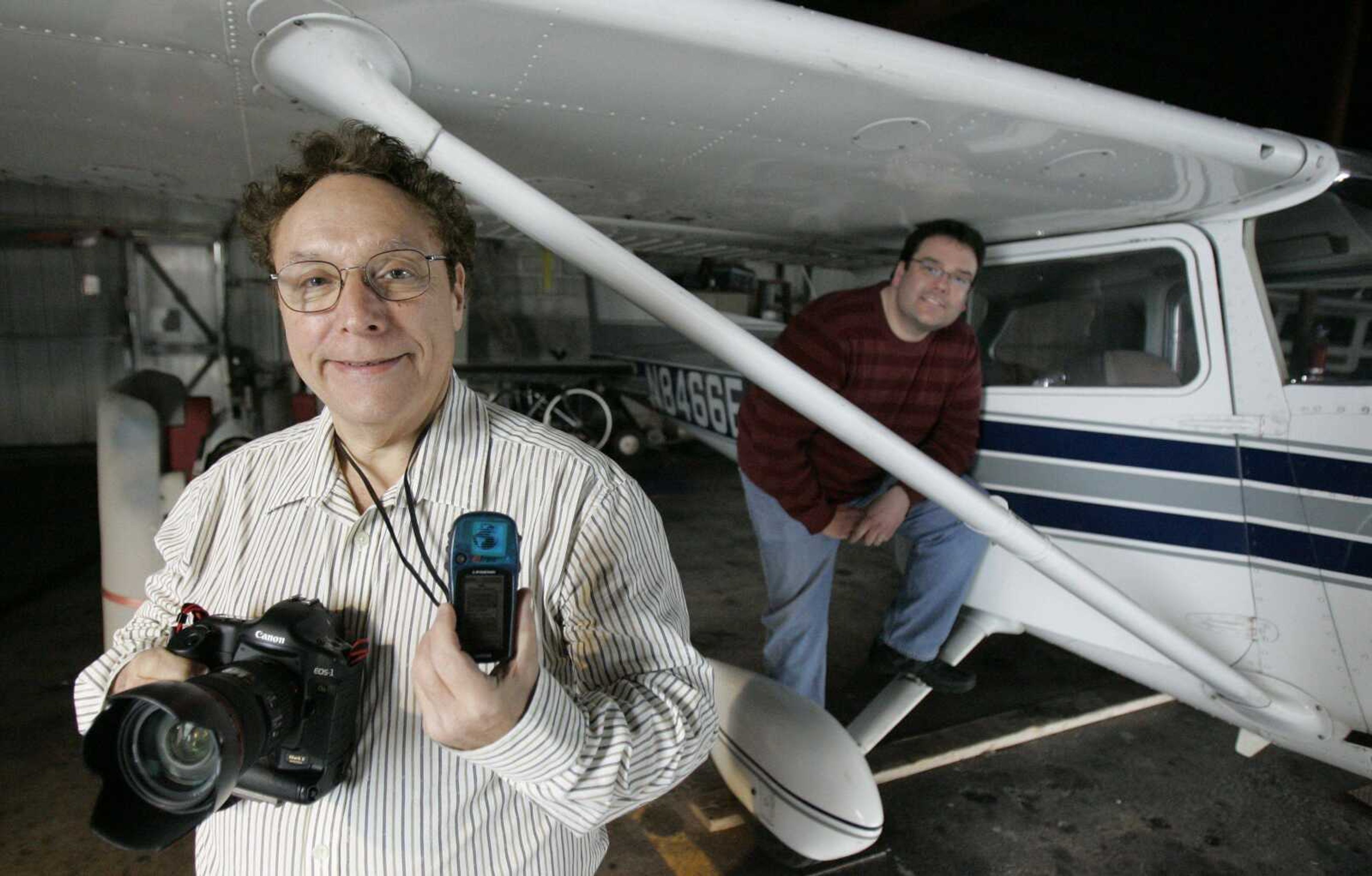 Aerial photographer Alan Goldstein, left, displayed a camera and a GPS mapping device Monday next to the plane he uses at the DuPage Airport in West Chicago, Ill. Pilot William Hamrick was at right. (M. Spencer Green ~ Associated Press)