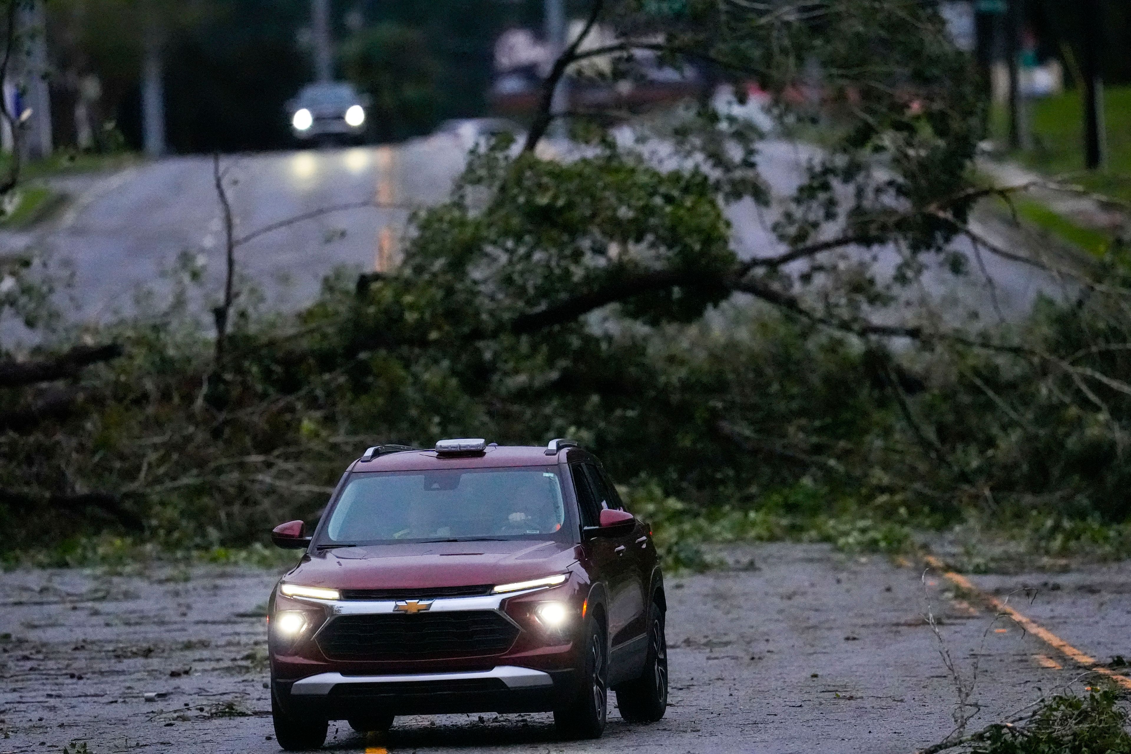 Vehicles move slowly around trees that have fallen after Hurricane Helene, Friday, Sept. 27, 2024, in Valdosta, Ga. (AP Photo/Mike Stewart)