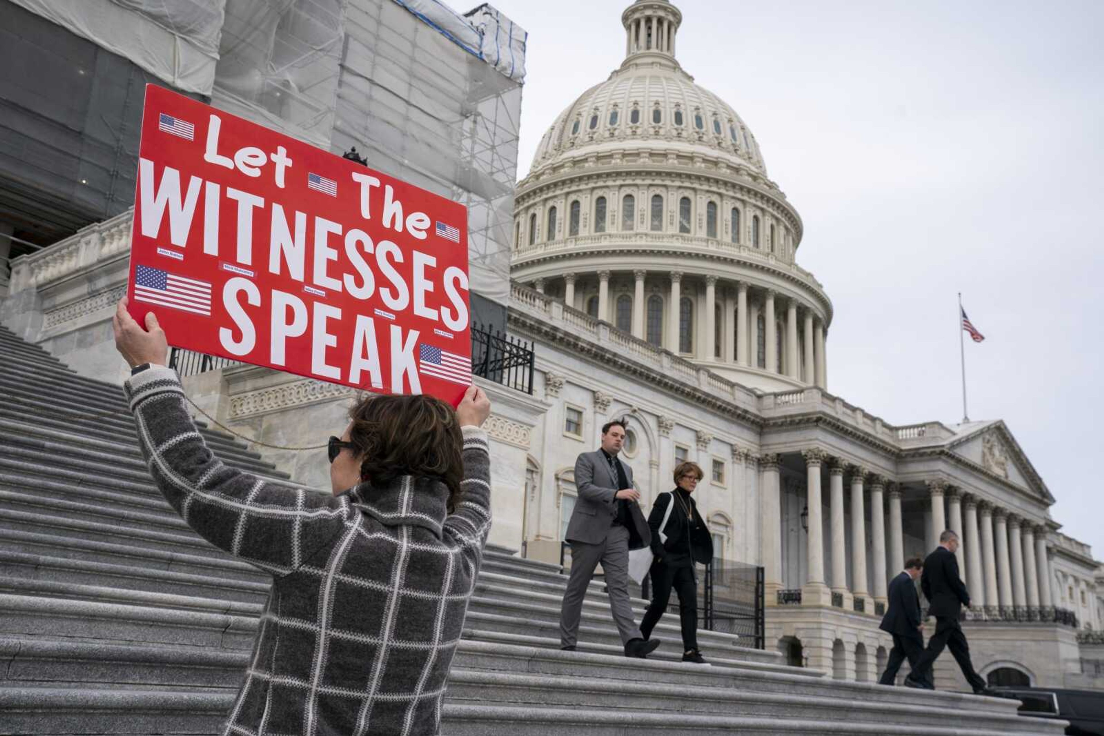 Laura Albinson of Pasadena, Maryland, displays a message Friday for members of the House as they leave the Capitol in Washington.