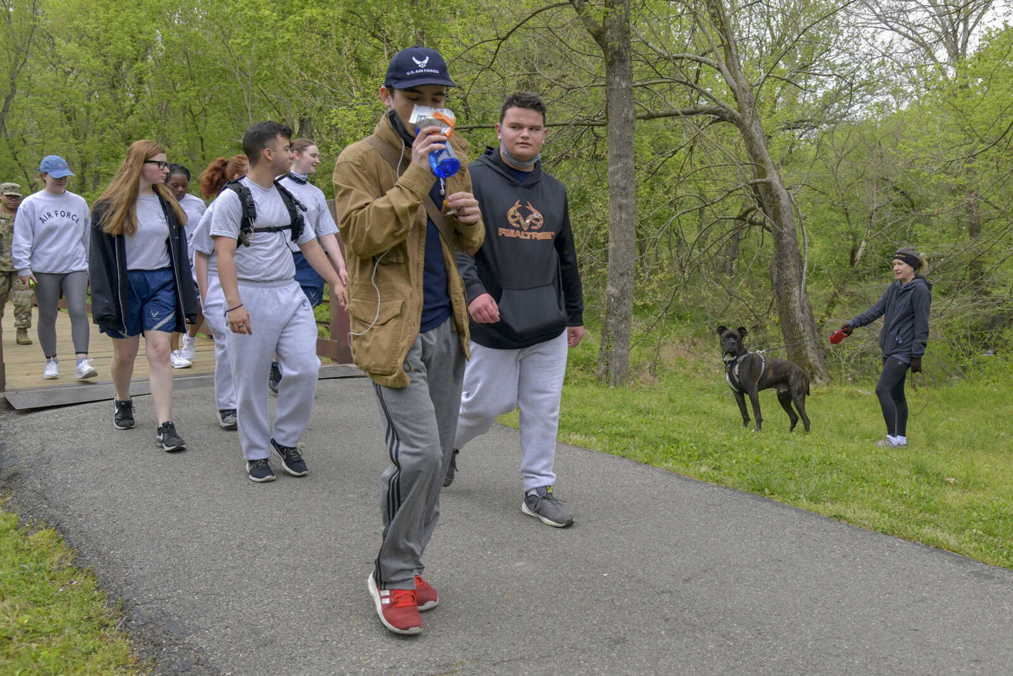 A person walking their dog stops to the side of the trail as Cape AFJROTC students walk on the Cape LaCroix Recreation Trail in the Cape Woods area during their commemorative Bataan Death March in Cape Girardeau on Saturday, April 17, 2021. (Sarah Yenesel ~ Southeast Missourian)
