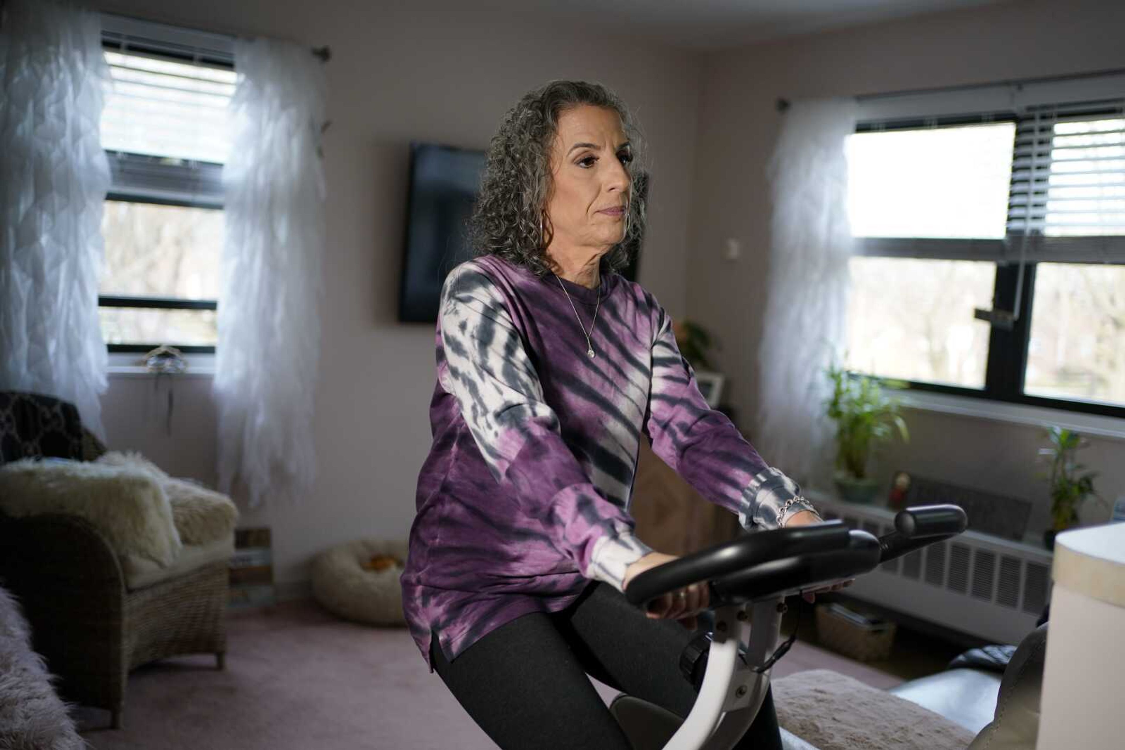 Catherine Busa rides an exercise bike as part of her recovery from COVID-19 on Jan. 13 at her home in New York. The 54-year-old New York City school secretary didn't have any underlying health problems when she caught the coronavirus in March and recovered at her Queens home. But some symptoms lingered. After eights months of suffering, she made her way to Jamaica Hospital Medical Center -- to a clinic specifically for post-COVID-19 care.