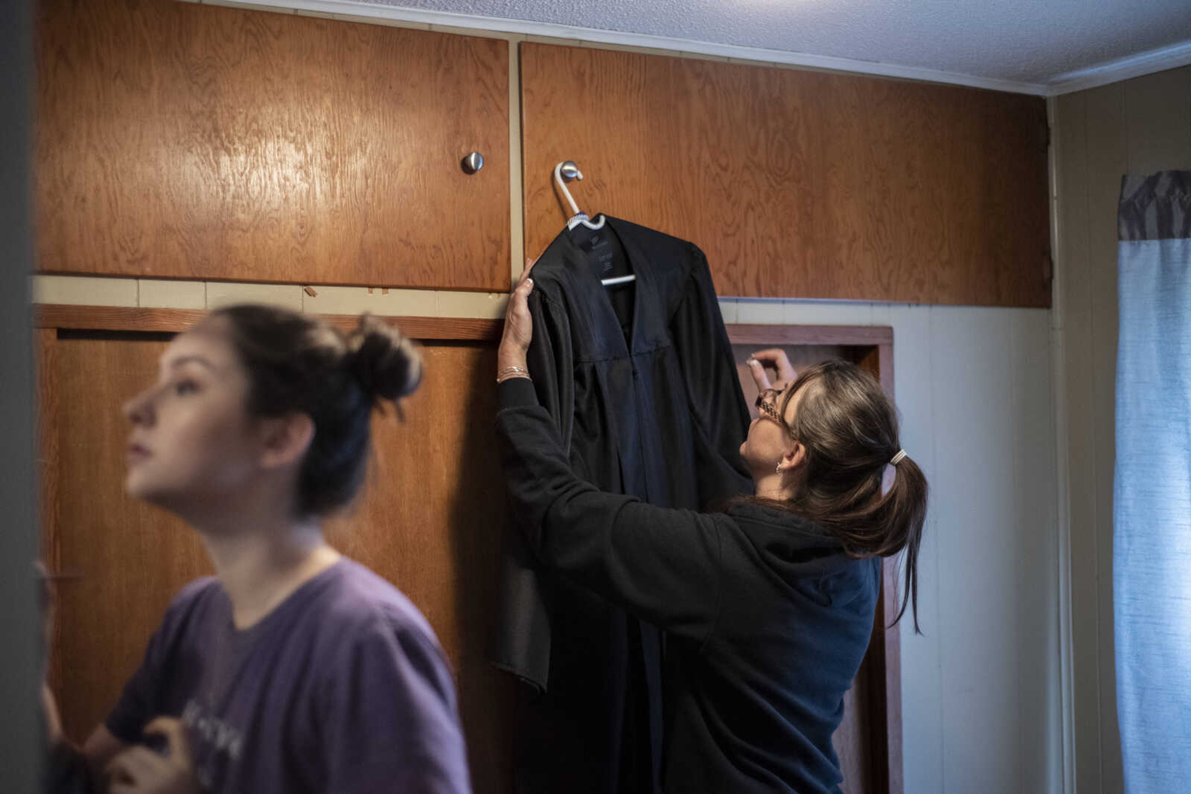 Missy Medlock hangs her daughter, Emily Medlock's, graduation gown up after ironing it while Emily does her makeup at home Sunday, May 12, 2019, in Cape Girardeau.