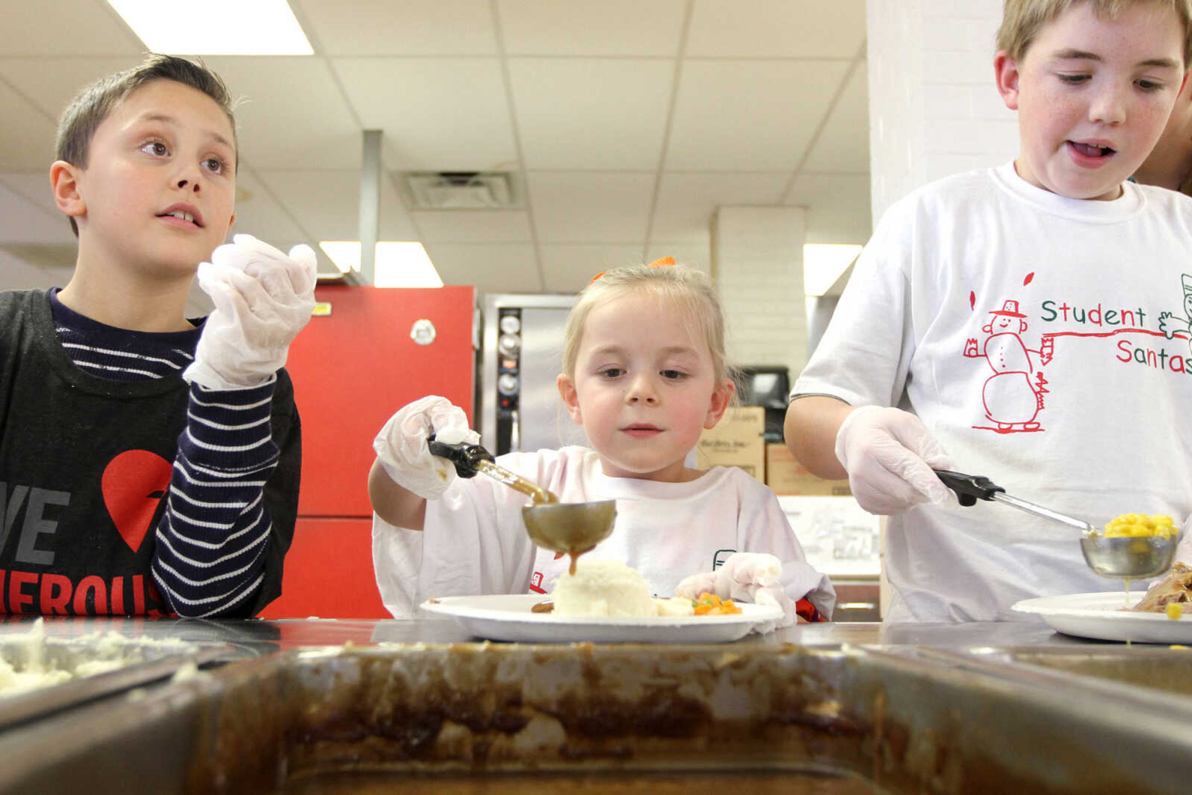 GLENN LANDBERG ~ glandberg@semissourian.com

Caleb Gast, left, Maya Stout and Gabe Stout serve up meals during the Student Santas Christmas dinner for families in need Thursday, Dec. 25, 2014 at Central Junior High School.