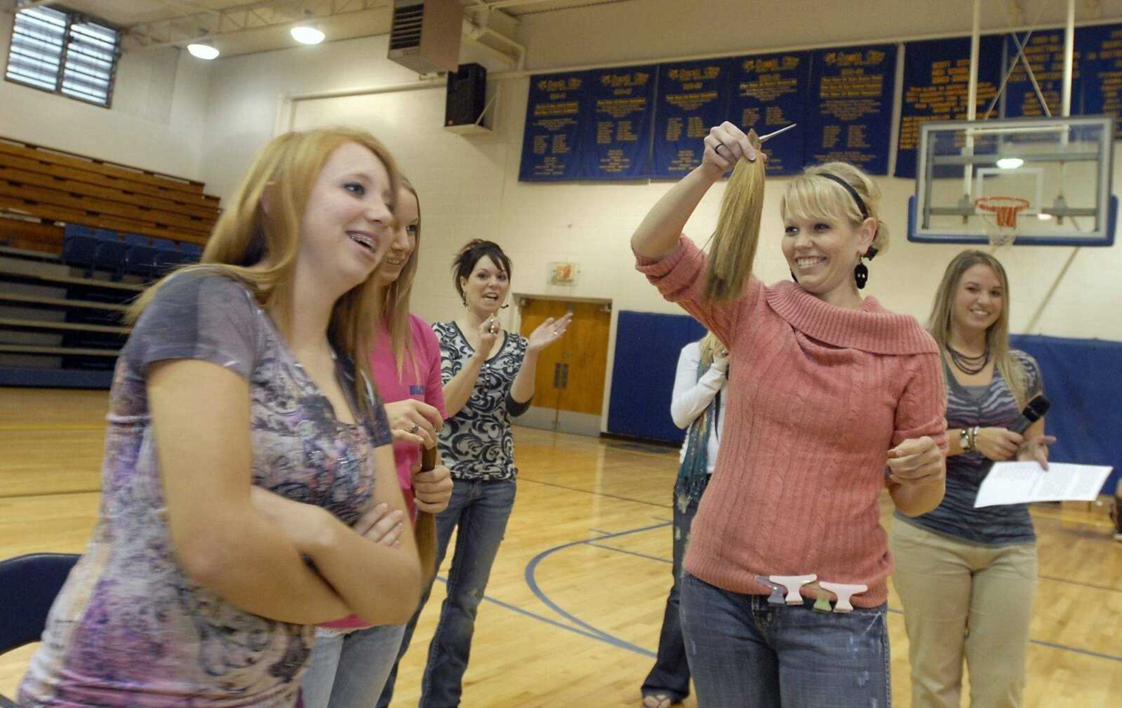 Cora Williams, of Style Studio, holds up the 10-inch section of hair she cut from tenth-grader Bryanna Sykes, left, during an assembly at Scott City High School on Friday, Oct. 29, 2010. Standing behind Williams and Sykes are, from left to right, fellow donor and tenth-grader Alexis Spriggs, Style Studio's Cortney Stubenrauch, and junior high science teacher Sara Bradshaw. Bradshaw was joined by students in donating their hair to Locks of Love. Bradshaw organized the donation in honor of her student Taylor Dudley, who has survived the most severe level of non-Hodgkin's lymphoma. (Kristin Eberts)