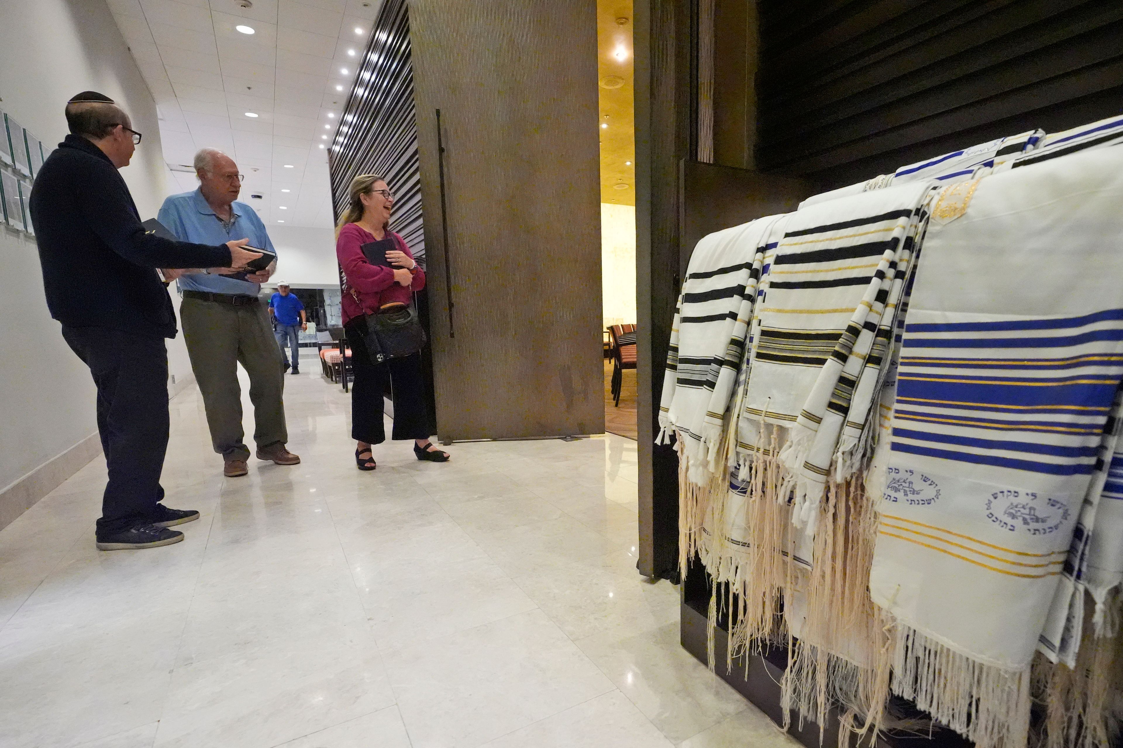 Craig Berko, left, director of membership at Temple Beth Sholom, hands out prayer books as people arrive to a Shabbat service, Friday, Sept. 27, 2024, in Miami Beach, Fla. (AP Photo/Wilfredo Lee)