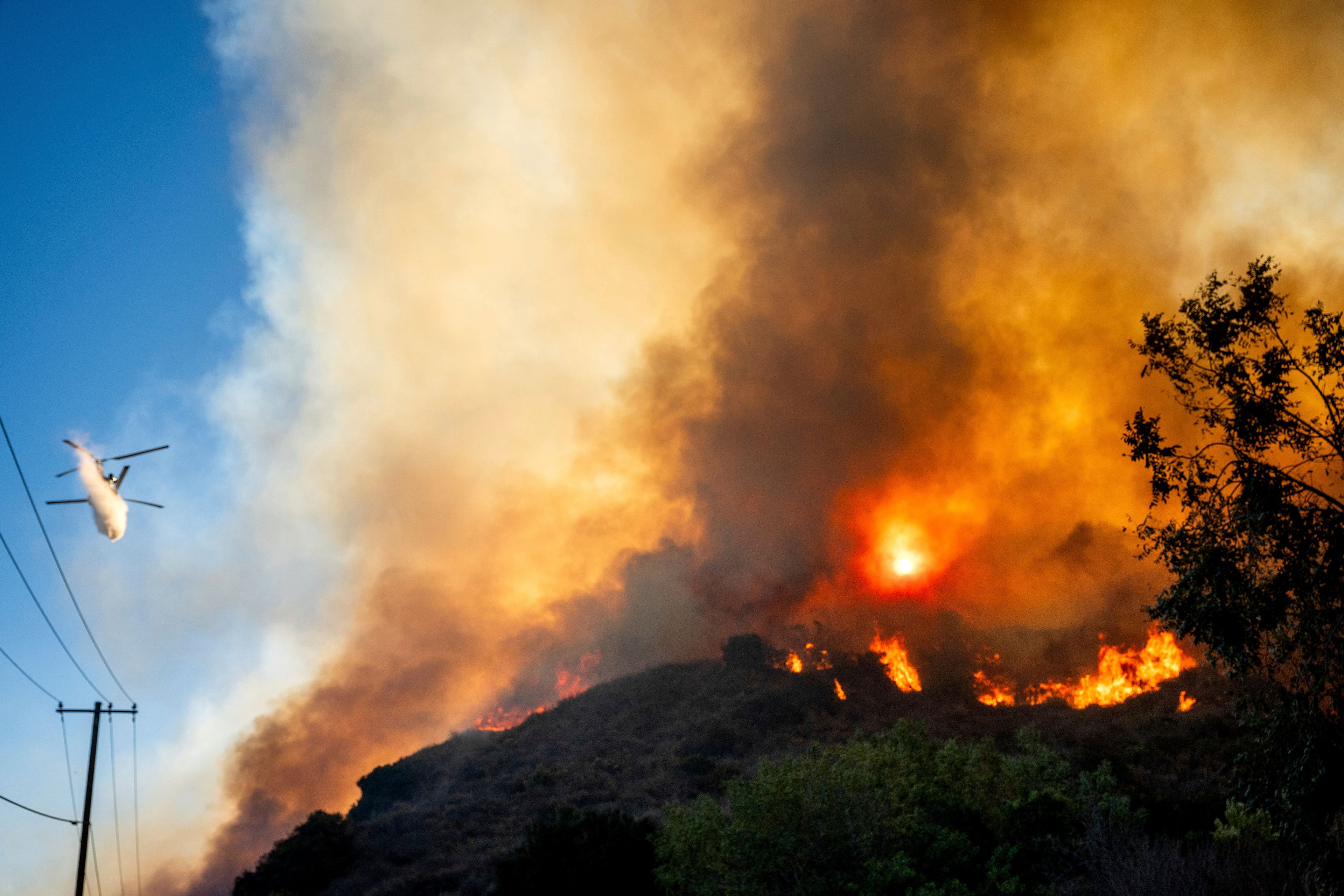 A helicopter drops water as the Mountain Fire burns along South Mountain Rd. on Thursday, Nov. 7, 2024, in Santa Paula, Calif. (AP Photo/Noah Berger)