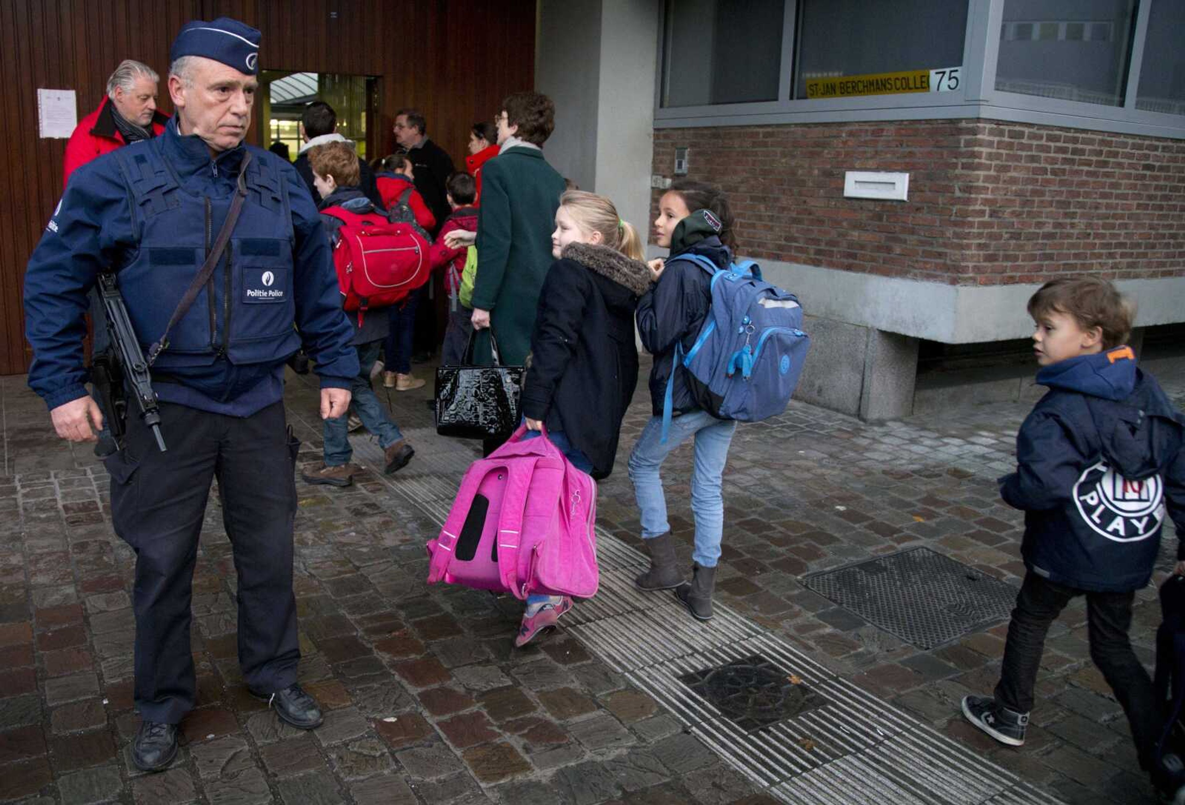 Children pass a police officer as they arrive for school Wednesday in the center of Brussels. (Virginia Mayo ~ Associated Press)