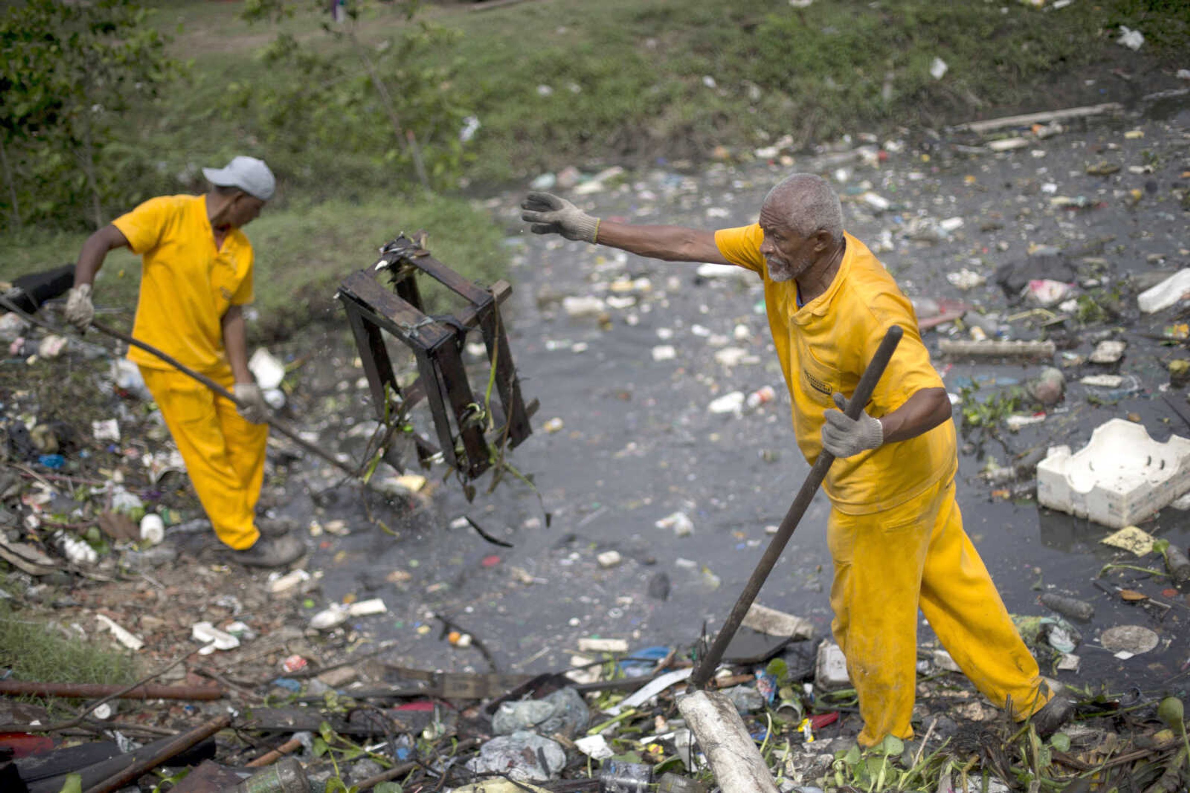 Workers remove garbage collected by floating waste barriers in the Meriti River, which flows into Guanabara Bay, on Nov. 5 in Rio de Janeiro, Brazil. (Silvia Izquierdo ~ Associated Press)