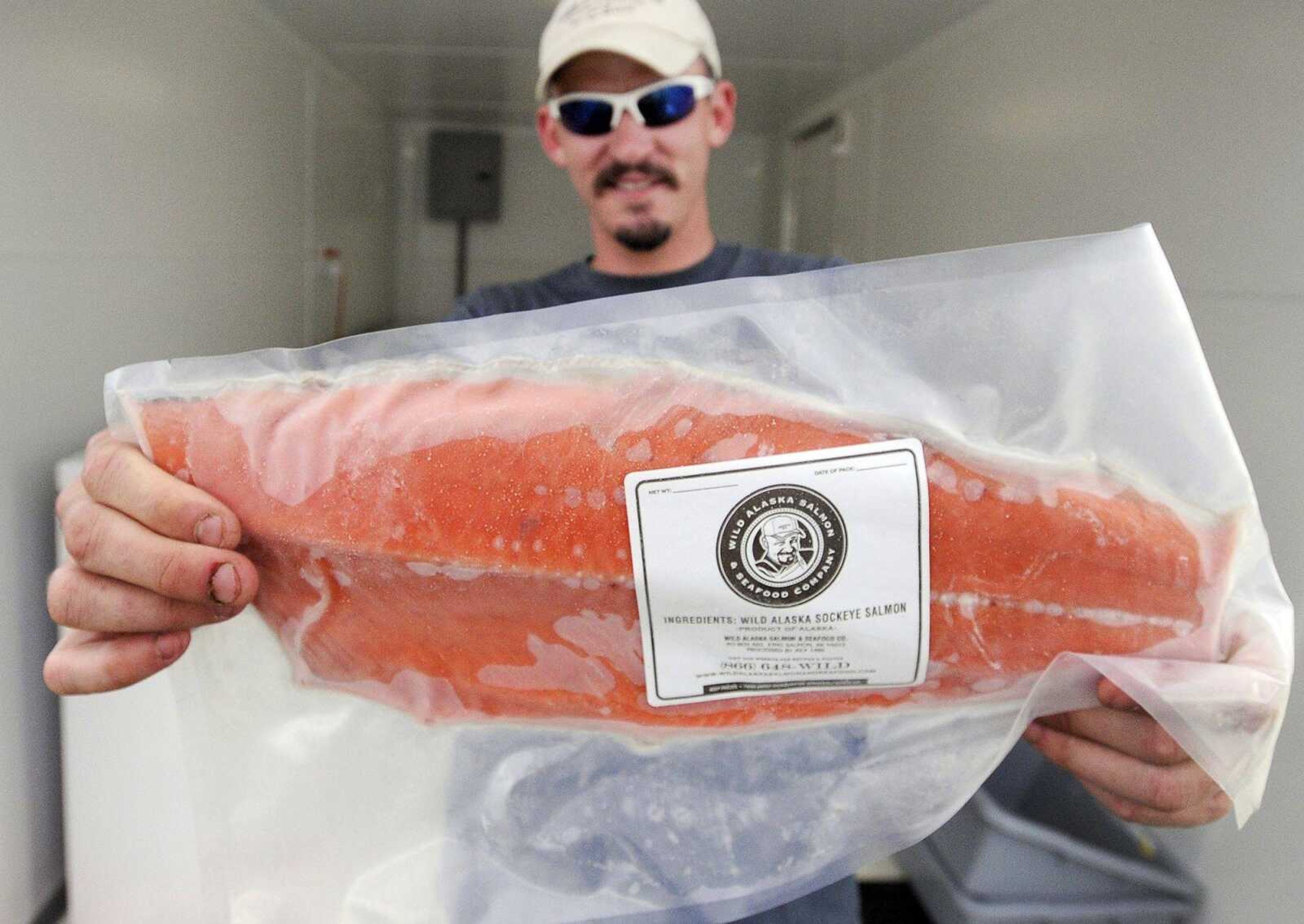 Trevor Tripp holds a salmon fillet at the Wild Alaska Salmon and Seafood Co. at the Cape Girardeau Farmers Market on Thursday afternoon.