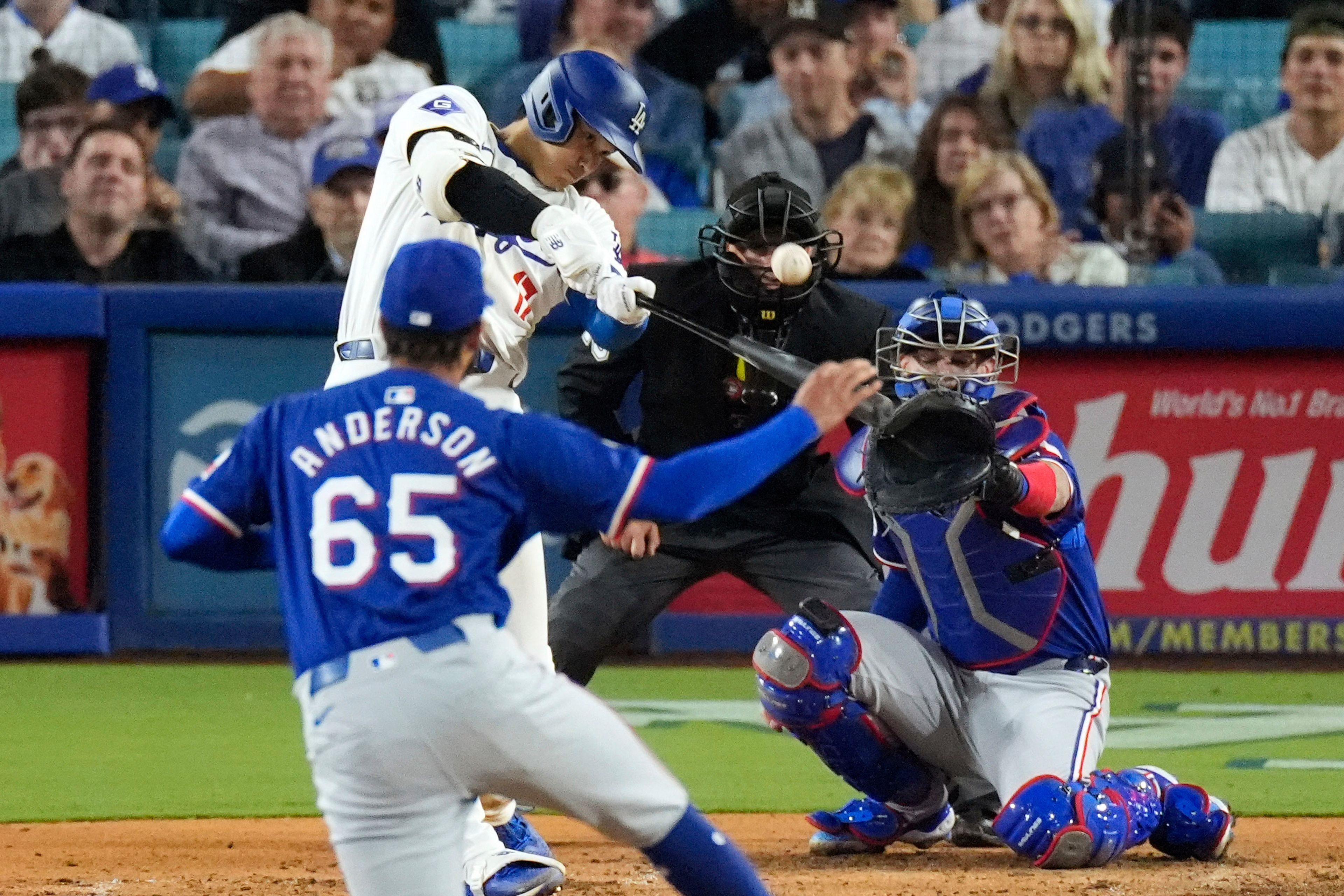 Los Angeles Dodgers' Shohei Ohtani, second from left, hits a two-run home run as Texas Rangers relief pitcher Grant Anderson, left, watches along with catcher Jonah Heim, right, and home plate umpire Nick Mahrley during the sixth inning of a baseball game Tuesday, June 11, 2024, in Los Angeles. (AP Photo/Mark J. Terrill)