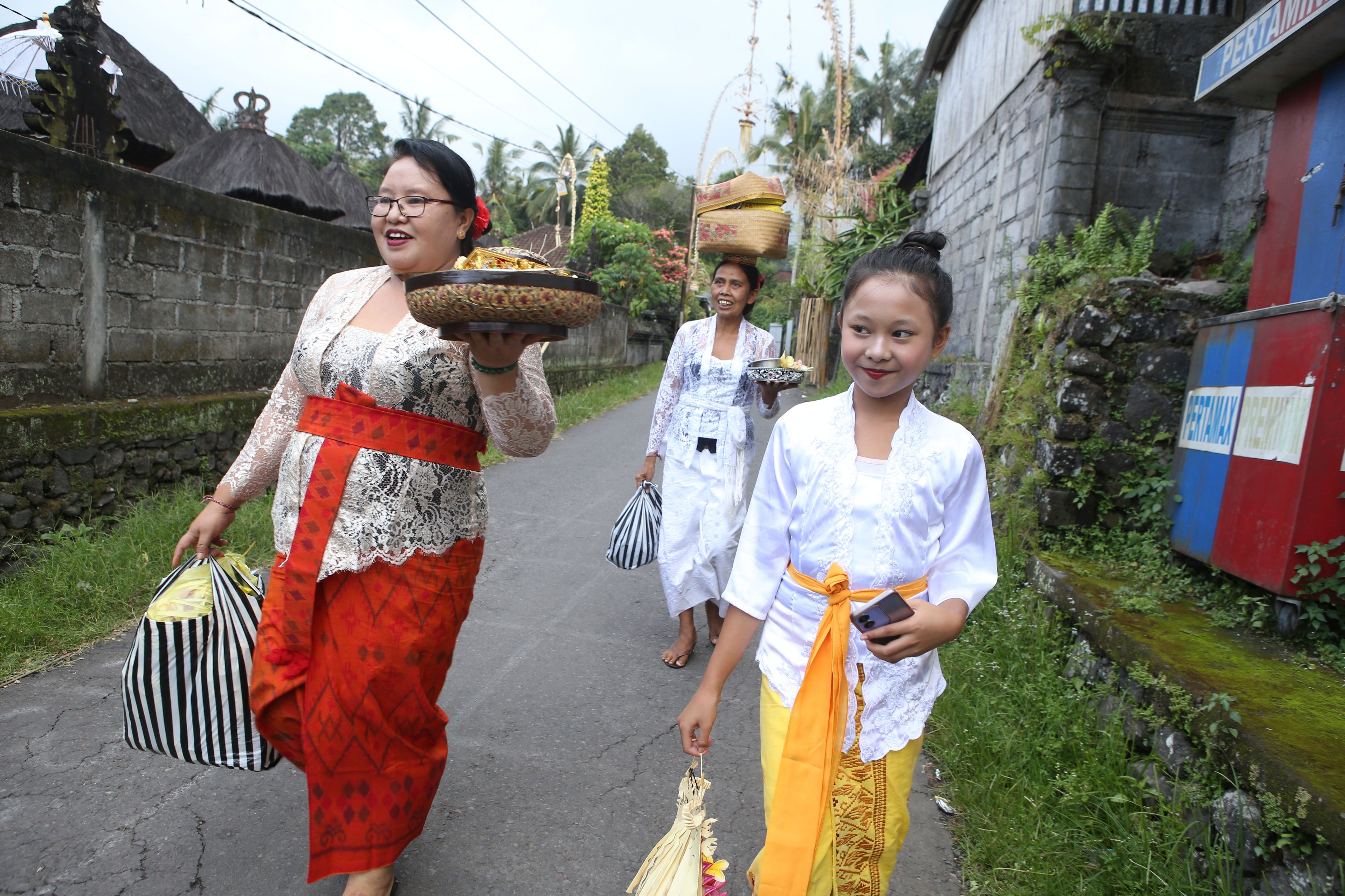 Kadek Krisni, left, walks with her daughter Ketut Nita Wahyuni, 11, to participate in a Hindu ceremony at Geriana Kauh village, Karangasem, Bali, Indonesia, Wednesday, Nov. 20, 2024. (AP Photo/Firdia Lisnawati)