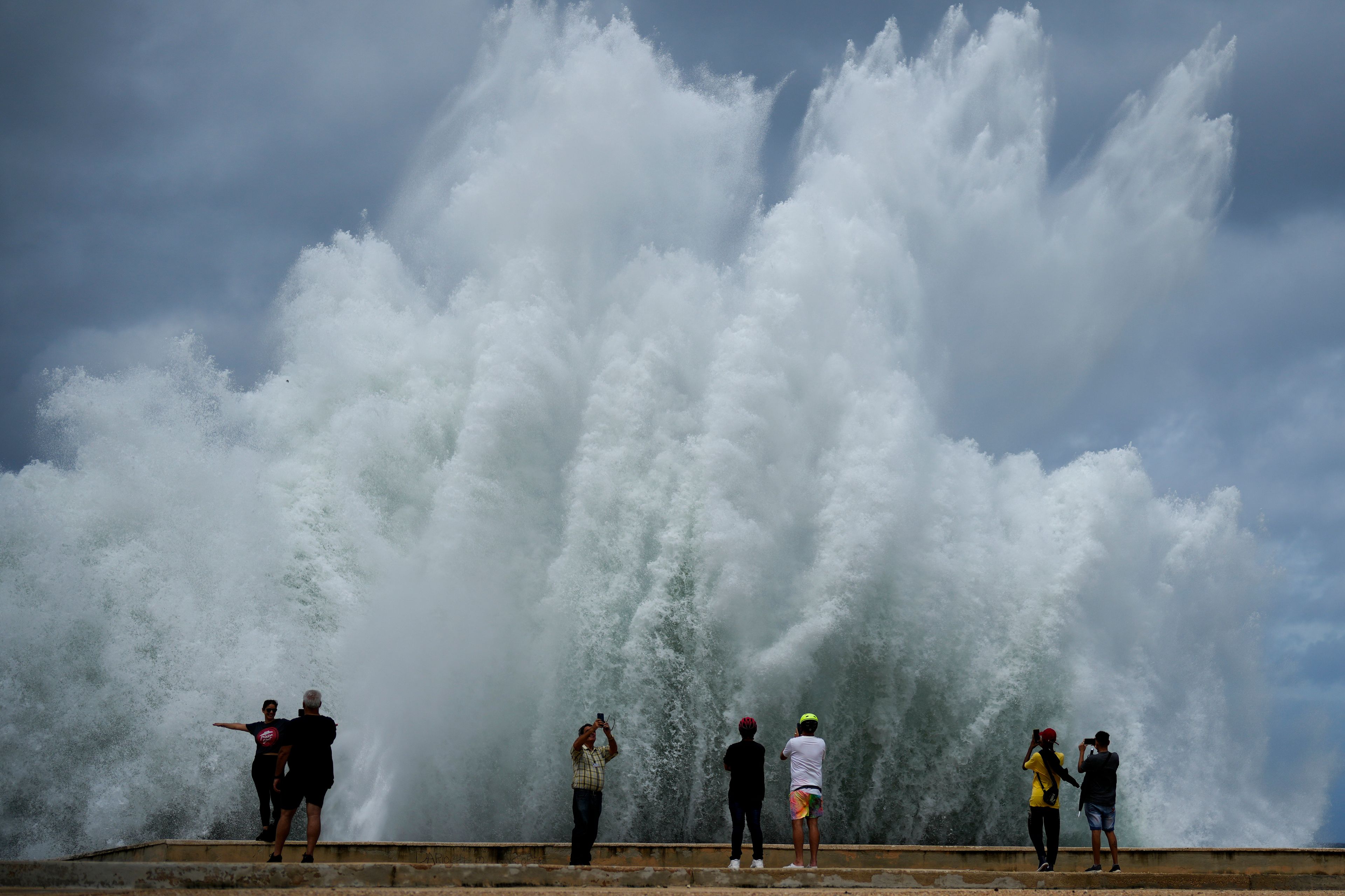 People take photos of the spray from waves crashing against the Malecon seawall, brought by the passing of Hurricane Milton in the Gulf of Mexico, in Havana, Cuba, Wednesday, Oct. 9, 2024. (AP Photo/Ramon Espinosa)