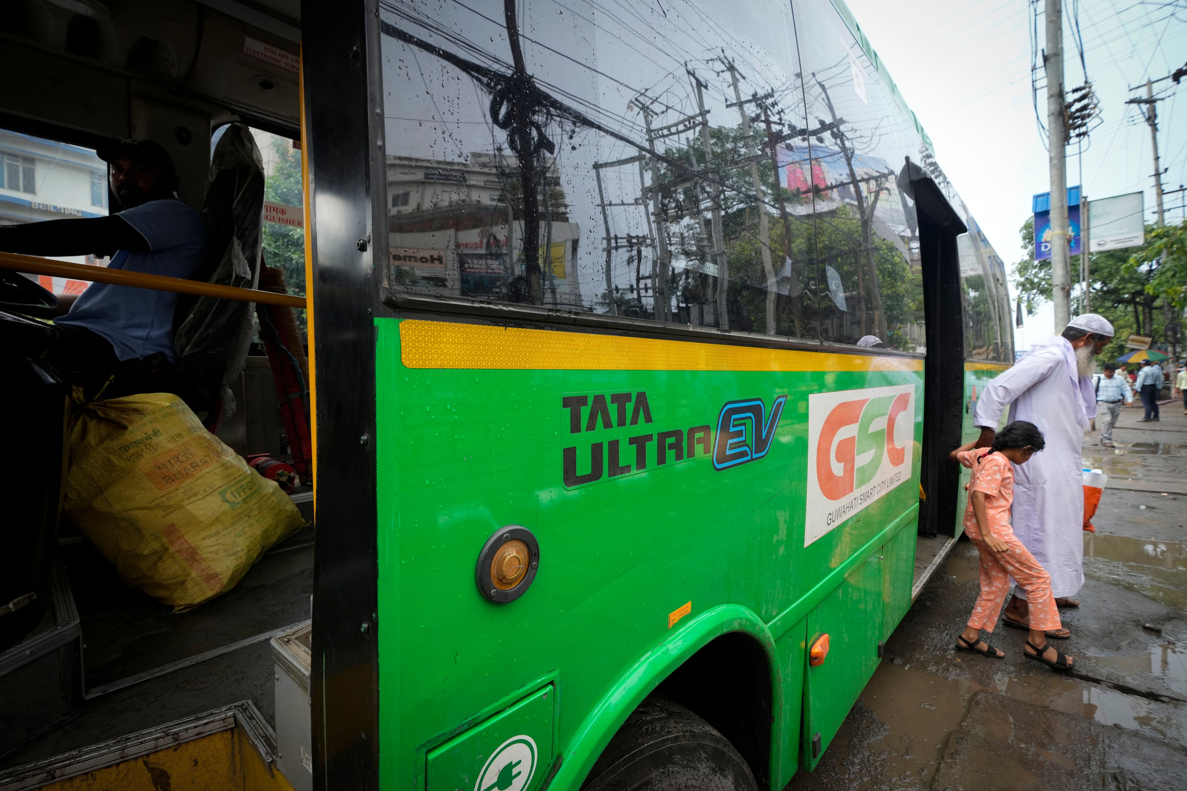 An elderly person gets down with a child from a Tata EV passenger bus in Guwahati, India, Thursday, Oct. 10, 2024. (AP Photo/Anupam Nath)