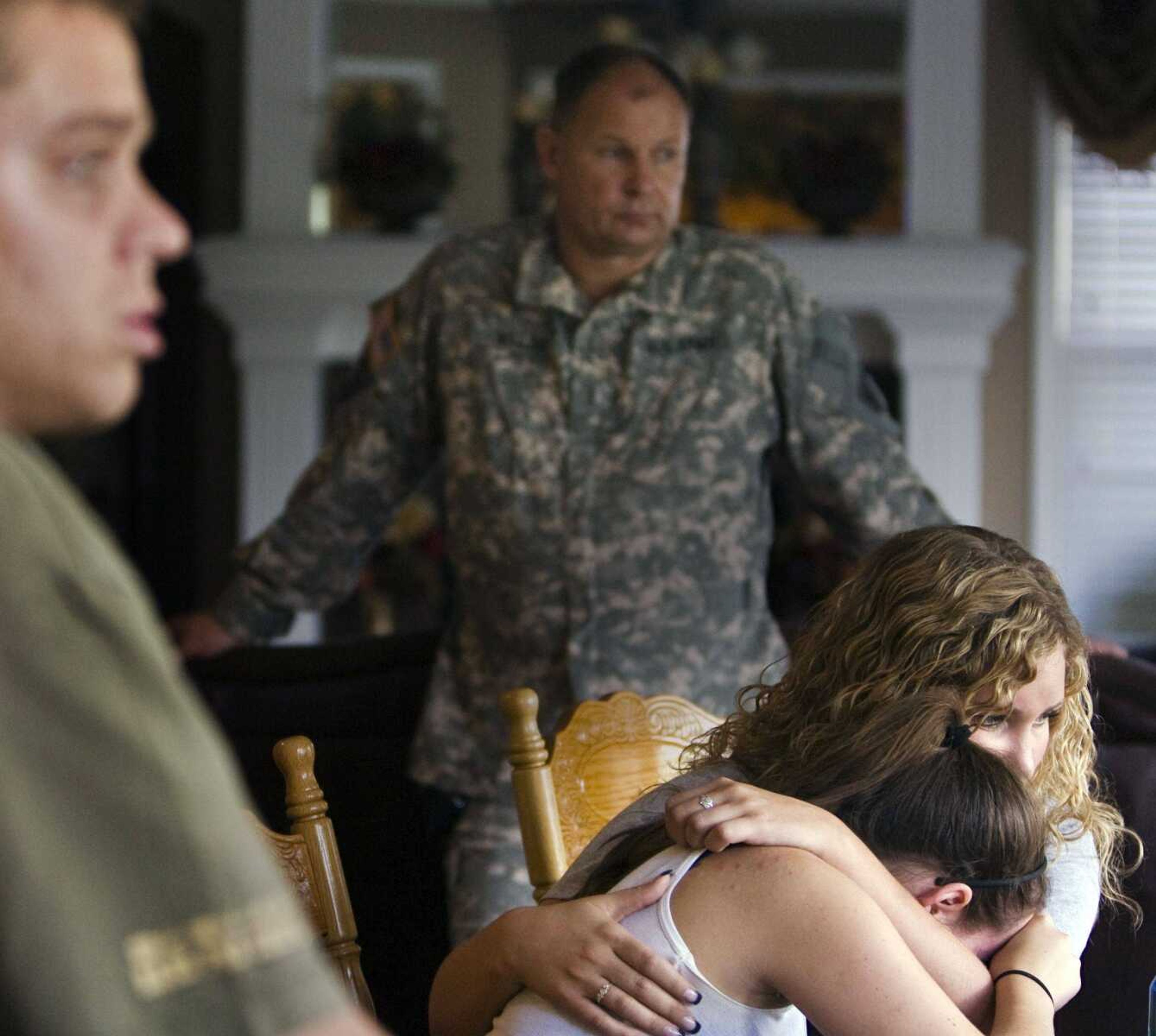 Jessica Daggs, 22, comforts Andrea Miller, 19, Sunday in Olathe, Kan., as Chief Warrant Officer Mike Walsh background, listens while talking about their friend Army Spc. Spencer Duncan, who was killed Saturday when his Chinook was shot down by insurgents in Afghanistan. (Allison Long ~ The Kansas City Star)