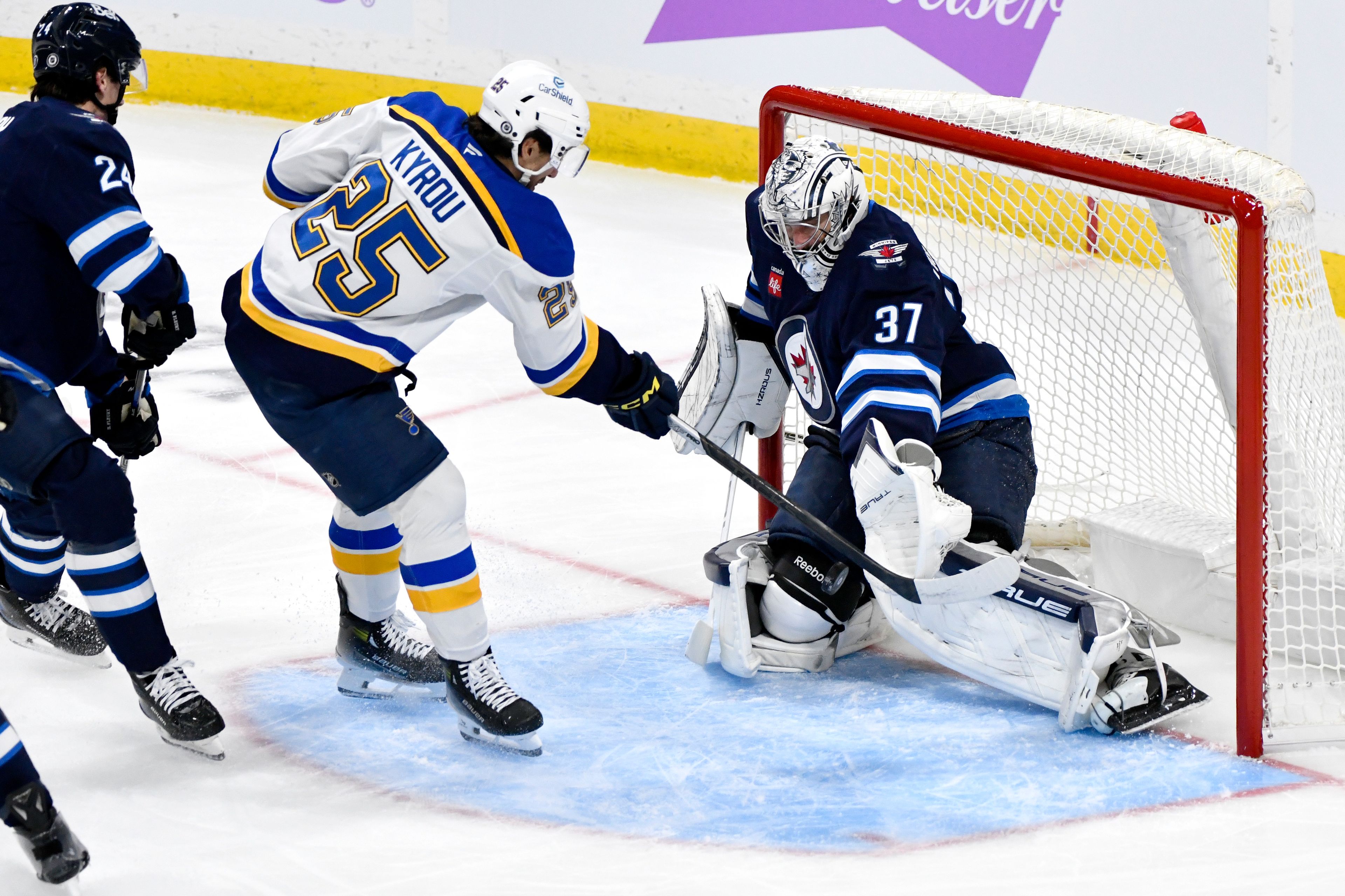 Winnipeg Jets goaltender Connor Hellebuyck (37) makes a save on St. Louis Blues' Jordan Kyrou (25) during the first period of their NHL hockey game in Winnipeg, Tuesday Dec. 3, 2024. (Fred Greenslade/The Canadian Press via AP)