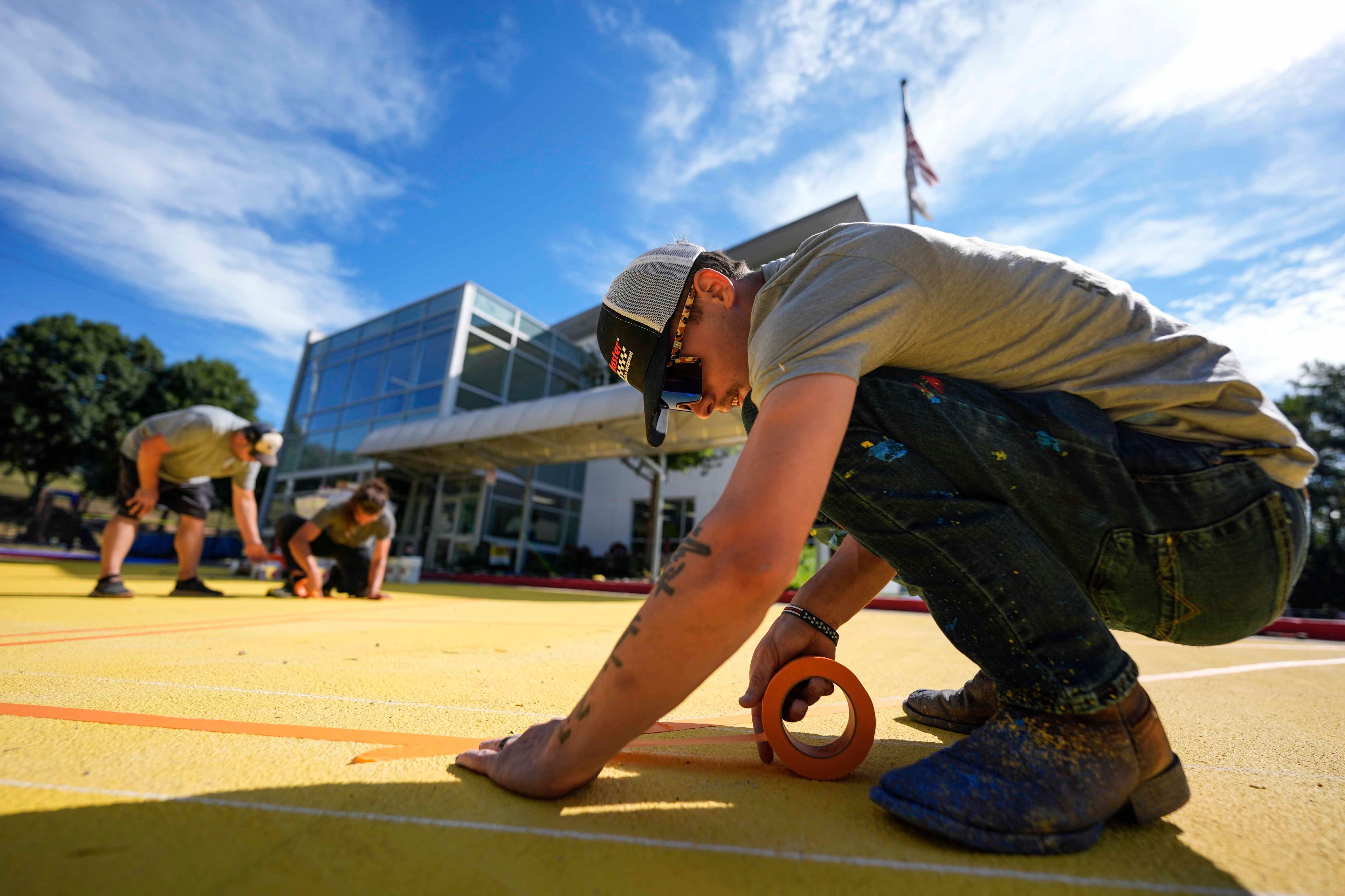 Ronnie Jefferies works on the parking lot at Science, Arts and Entrepreneurship School where it is being repainted to help cool it by making it more reflective, Wednesday, Sept. 4, 2024, in Mableton, Ga. (AP Photo/Mike Stewart)