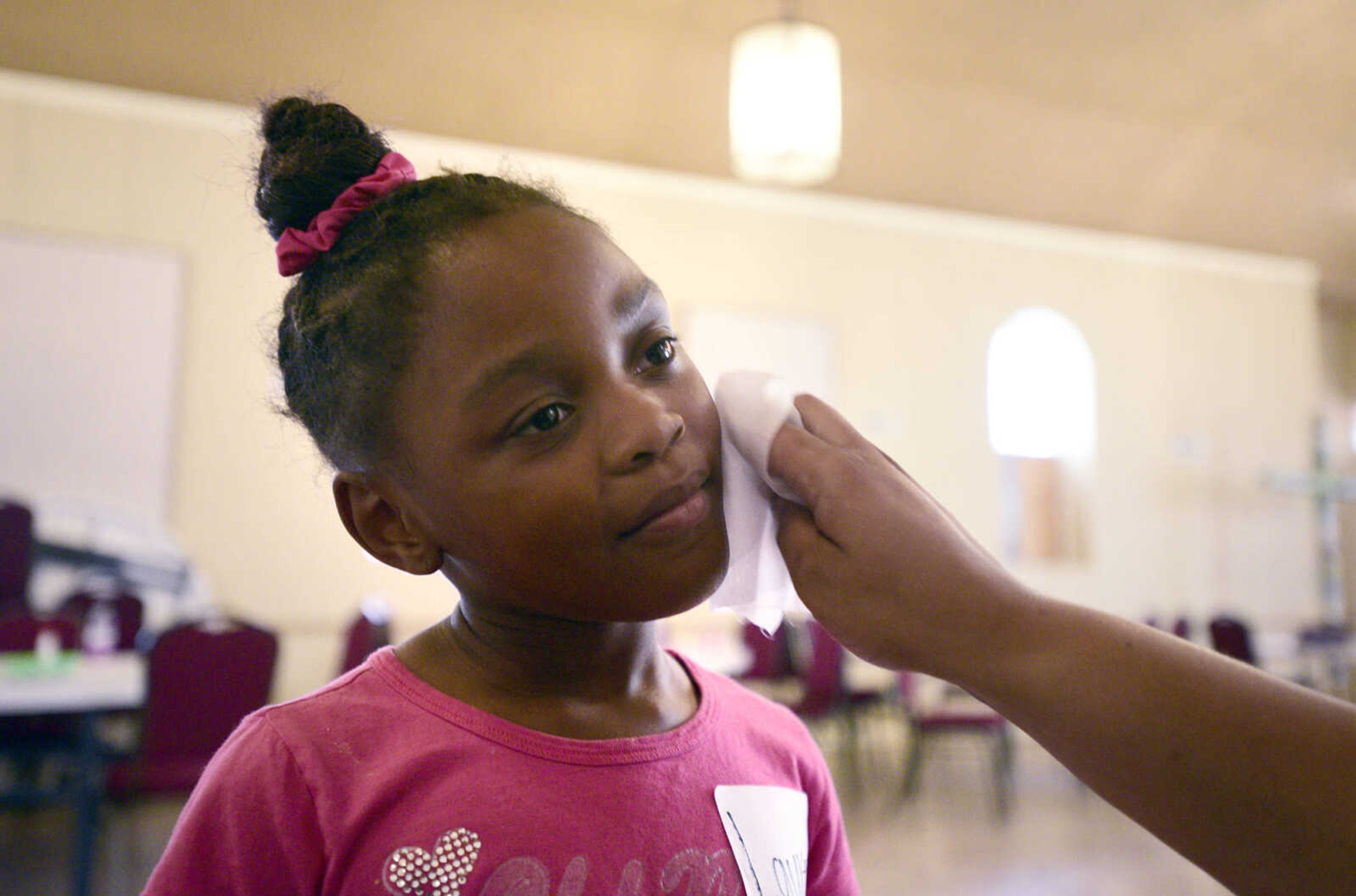 Cherish Moore wipes donut glaze off of Lauren Washington on Monday, Aug. 14, 2017, during the Salvation Army's after school program at The Bridge Outreach Center in Cape Girardeau.