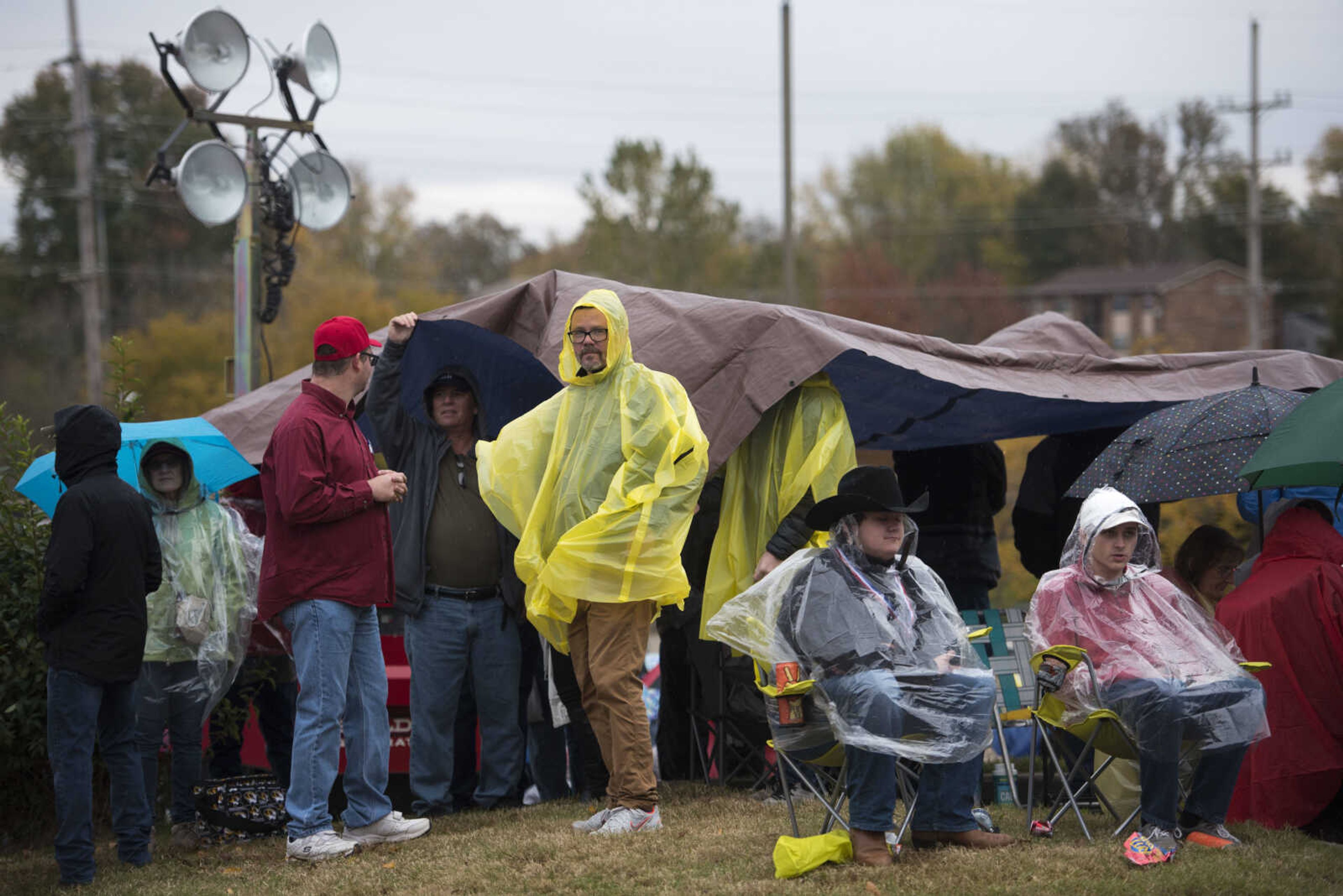 Trump supporters use ponchos and tarps for shelter from the rain while waiting in line for a Make America Great Again rally Monday, Nov. 5, 2018, at the Show Me Center in Cape Girardeau.