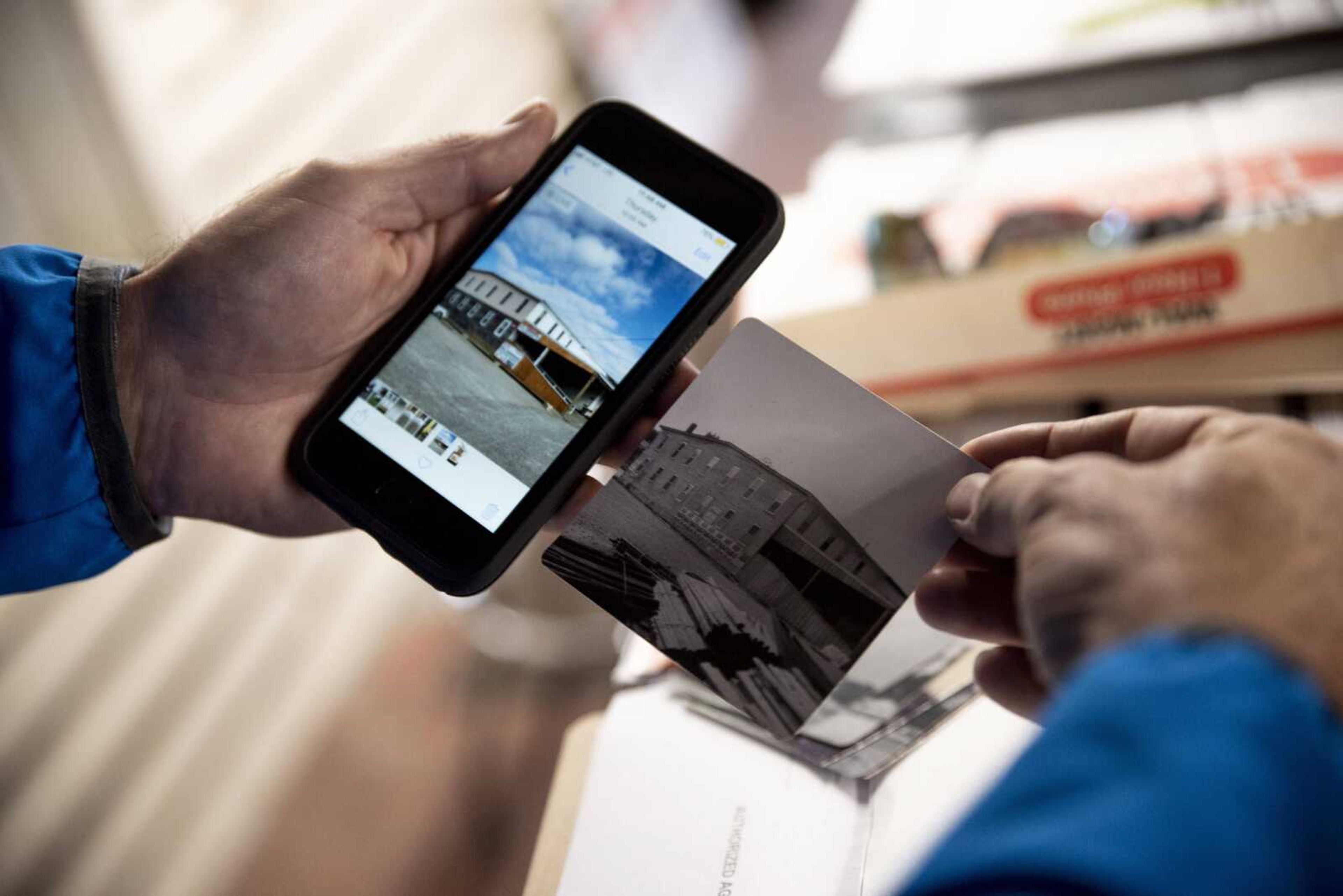 Phil Leimer shows a printed photo, right, of the original mill compared to the new building front of Mill Warehouse Building Supply on Tuesday in Jackson.