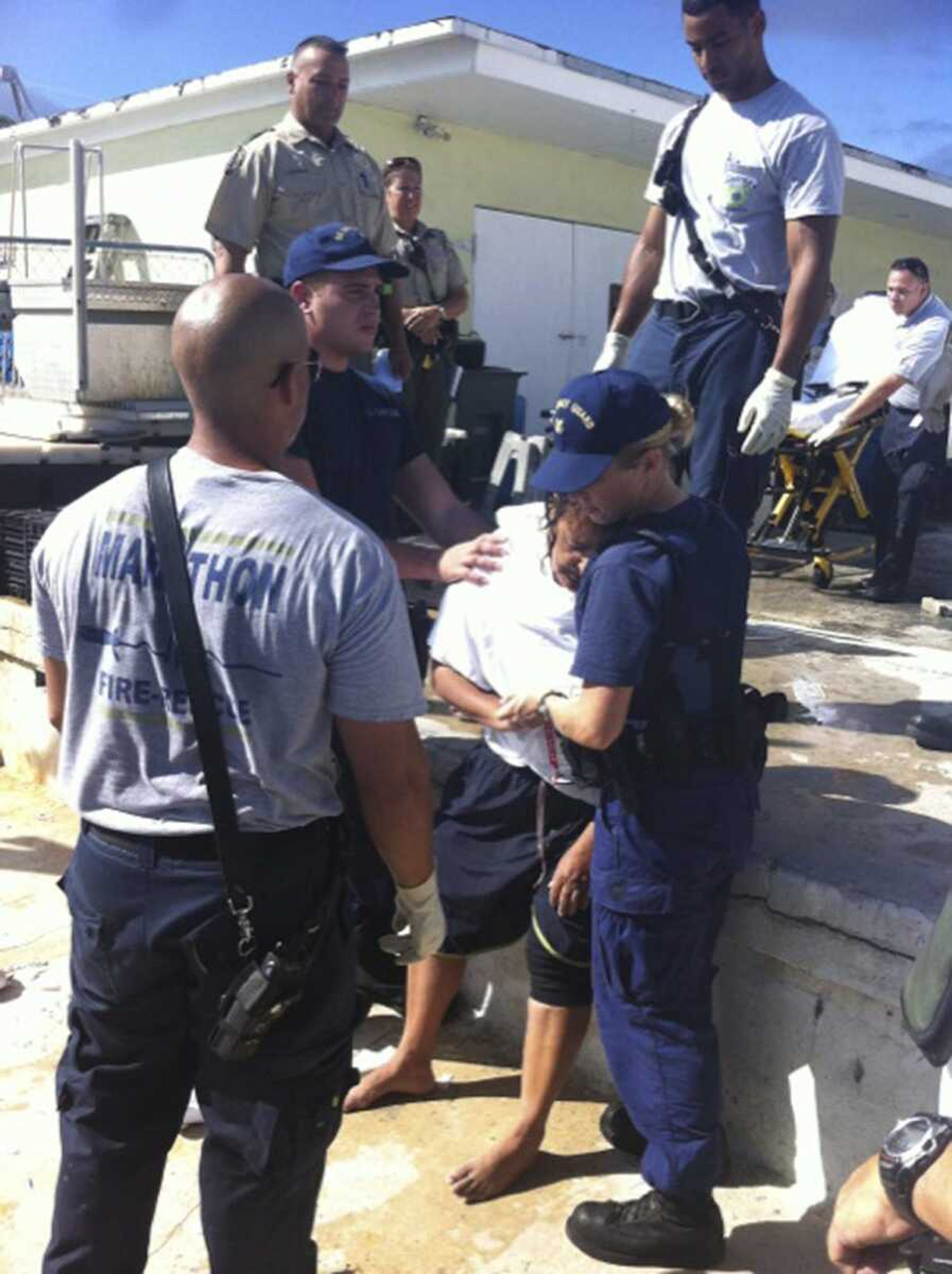 Seaman Kendra Graves, right, and Petty Officer 3rd Class Robert Femia assist EMS personnel in Marathon, Fla., with one of seven boaters rescued after treading water for around 20 hours Sunday.
(U.S. Coast Guard)