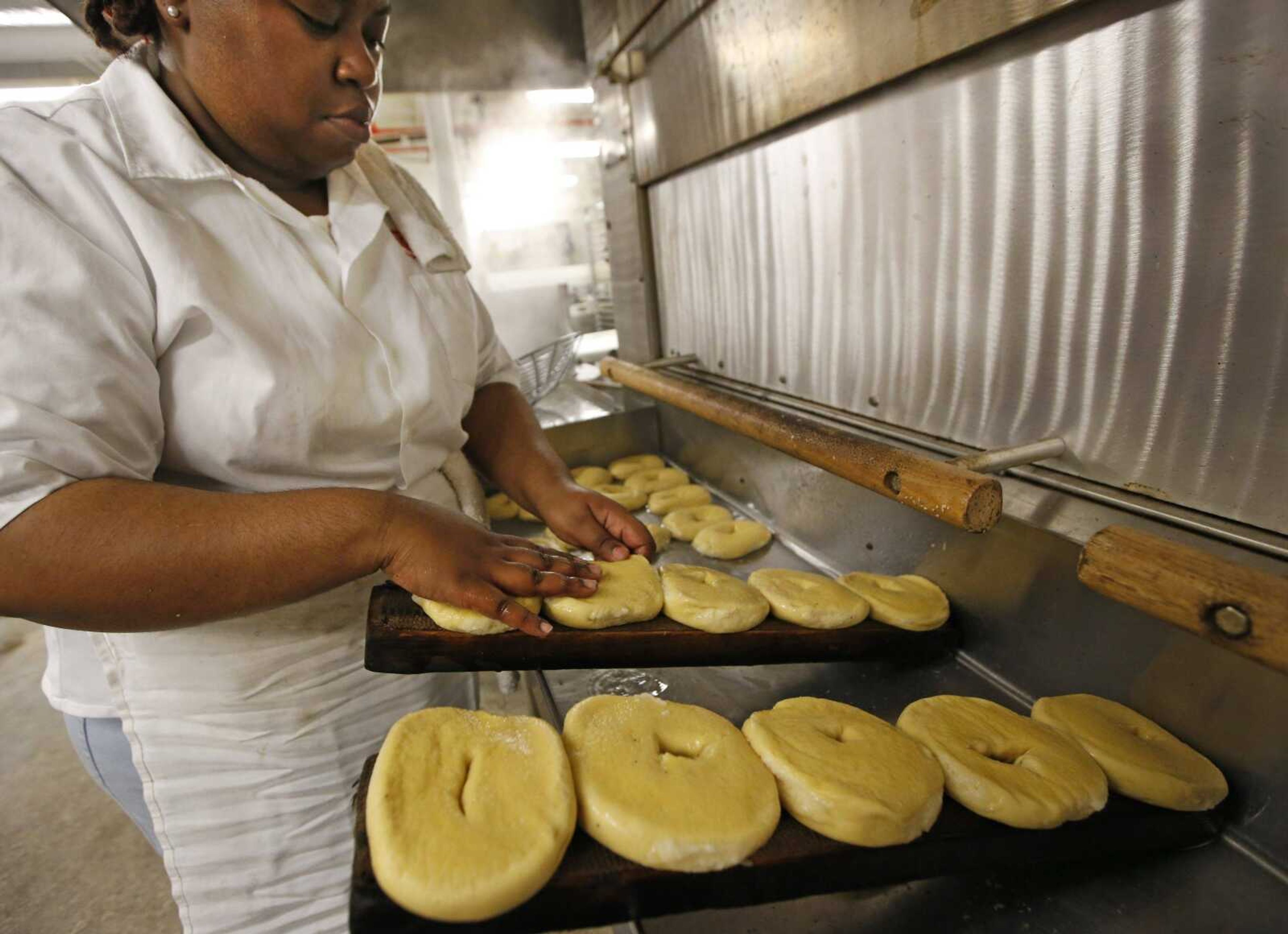 Bagel maker Sharelle Robbins places boiled bagels on burlap-covered wooden planks before placing them in the oven May 26 at Kossar's Bagels & Bialys in New York. One of Kossar's owners, David Zablocki, says the wood helps the bagels achieve a crispy bottom and nicely browned top.