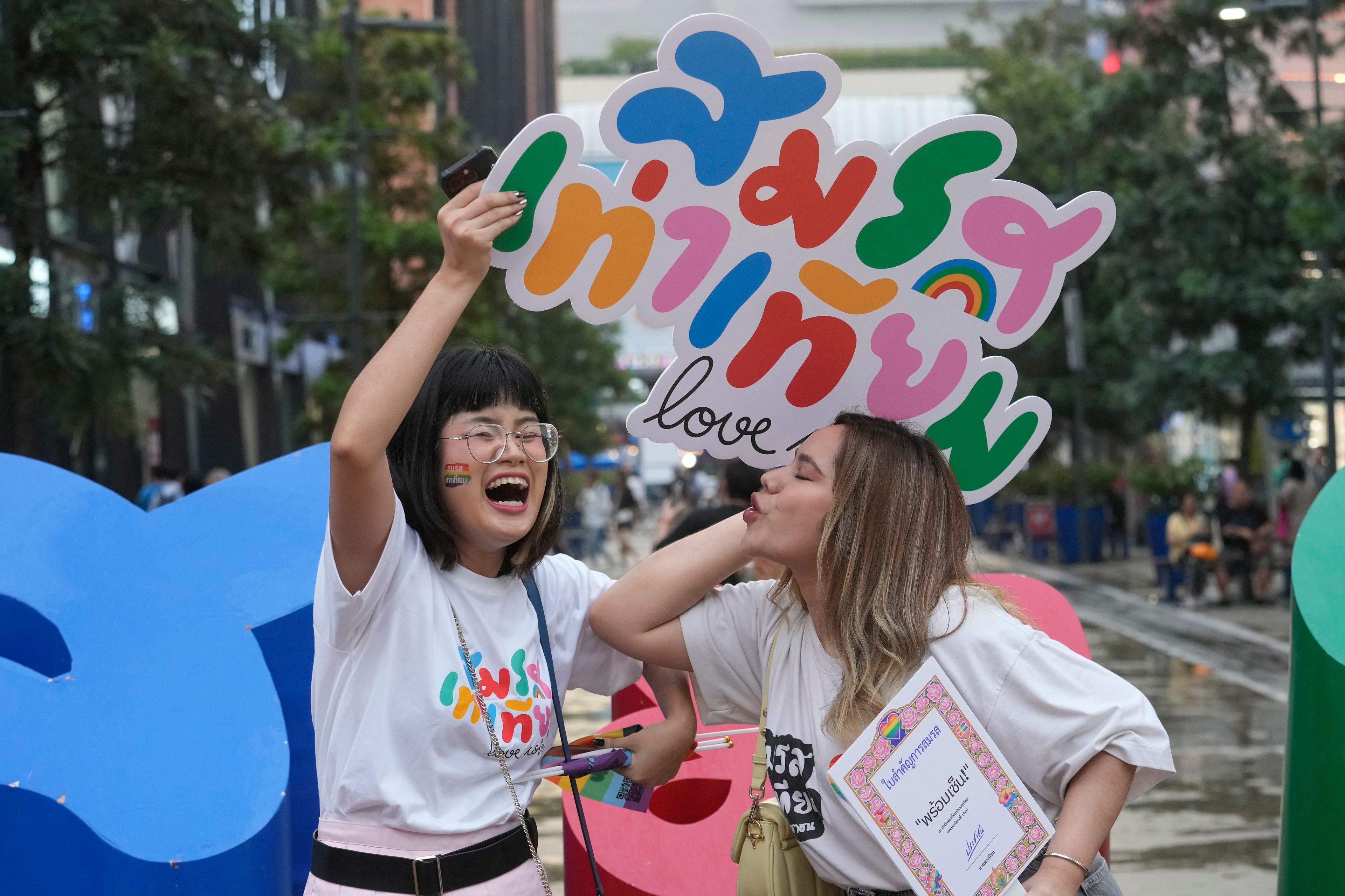 Participants hold posters celebrating marriage equality in Bangkok, Thailand, Wednesday, Sept. 25, 2024. (AP Photo/Sakchai Lalit)