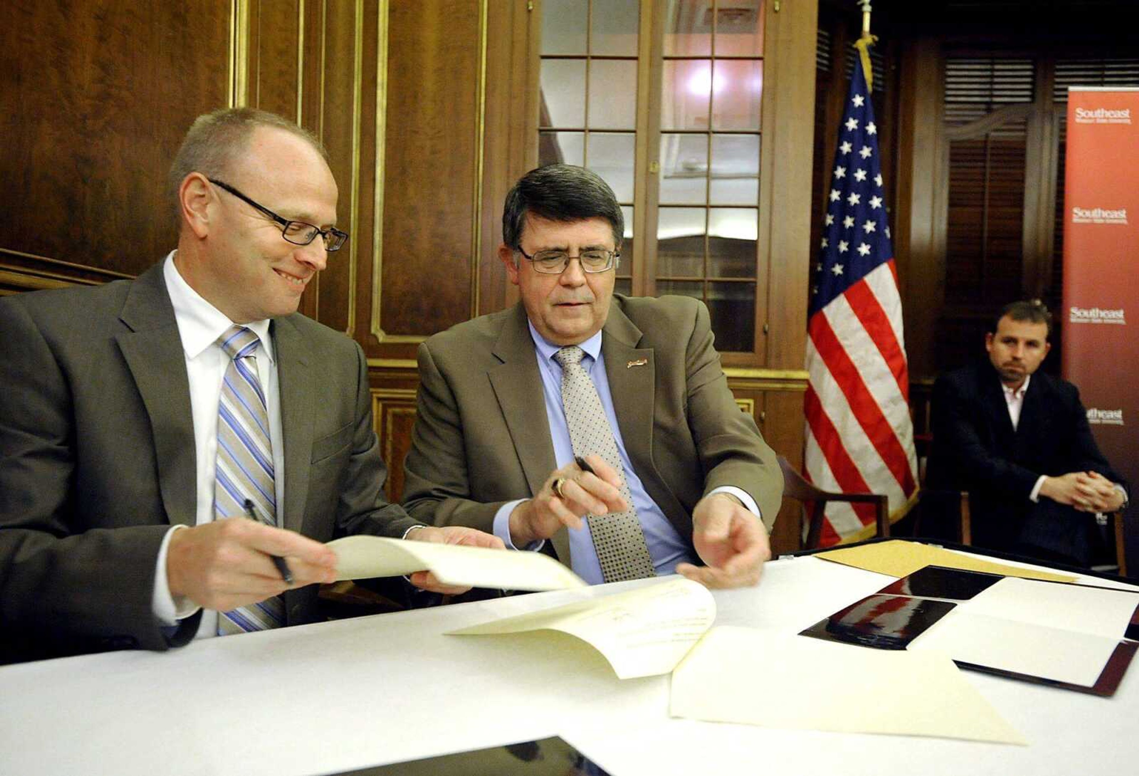 Former Missouri House speaker Steve Tilley watches in the background as Mineral Area College president Dr. Steven Kurtz, left, and Southeast Missouri State president Dr. Ken Dobbins sign a reverse transfer agreement Monday at the Perryville Higher Education Center. (Laura Simon)