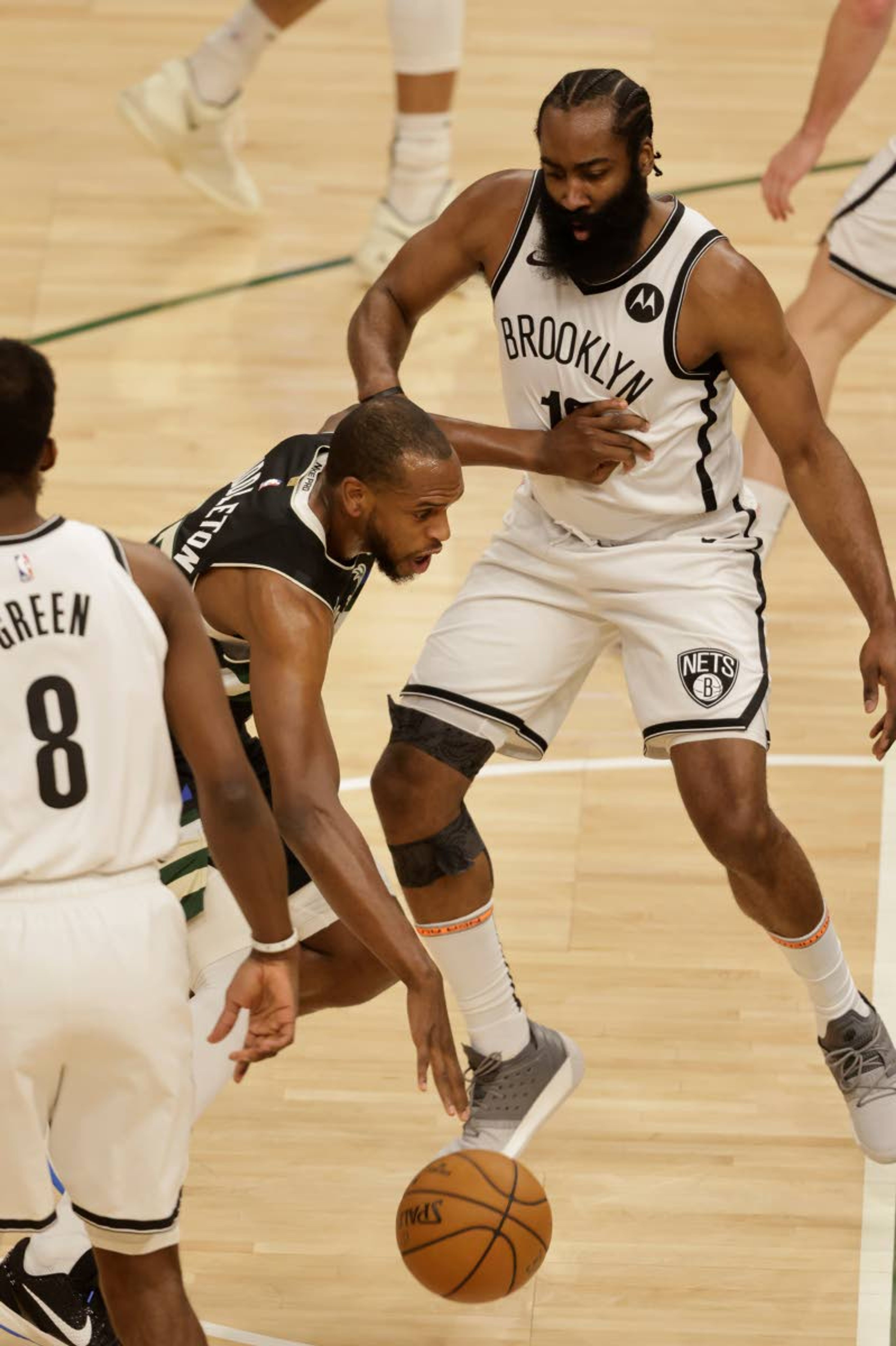 Milwaukee Bucks forward Khris Middleton, center, drives against Brooklyn Nets guard James Harden, right, during the first half of Game 6 of a second-round NBA basketball playoff series Thursday, June 17, 2021, in Milwaukee. (AP Photo/Jeffrey Phelps)