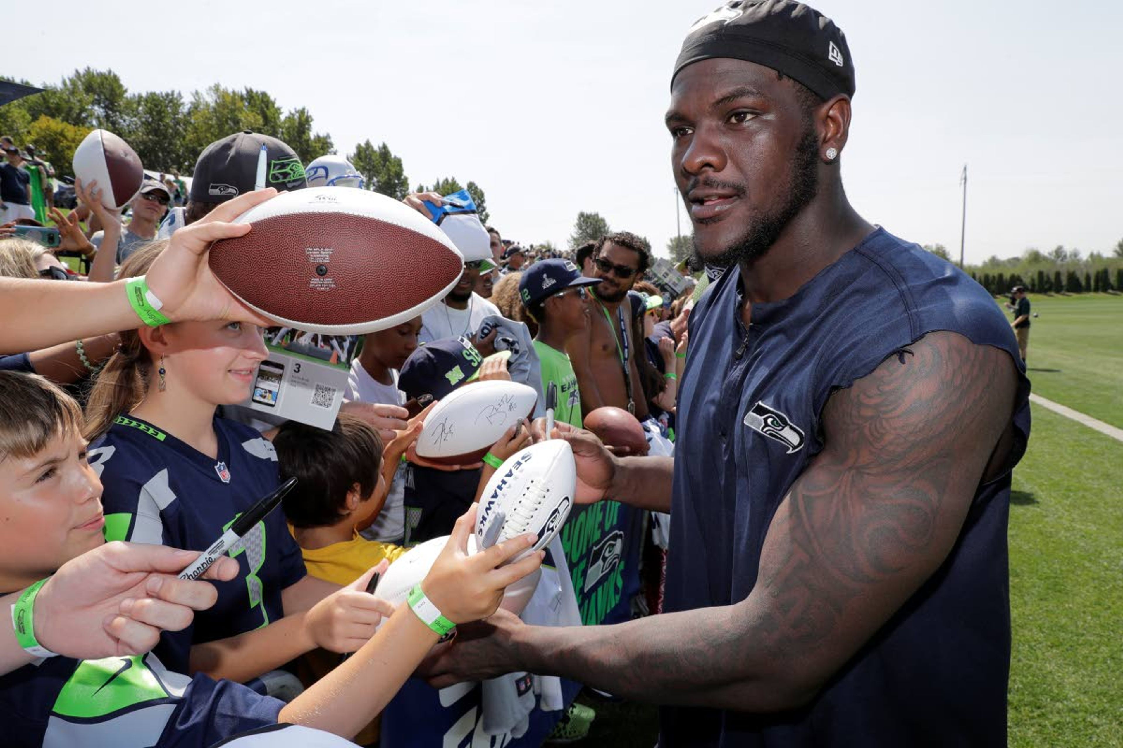 Seahawks’ defensive end Frank Clark signs autographs following NFL football training camp Aug. 6 in Renton, Wash.