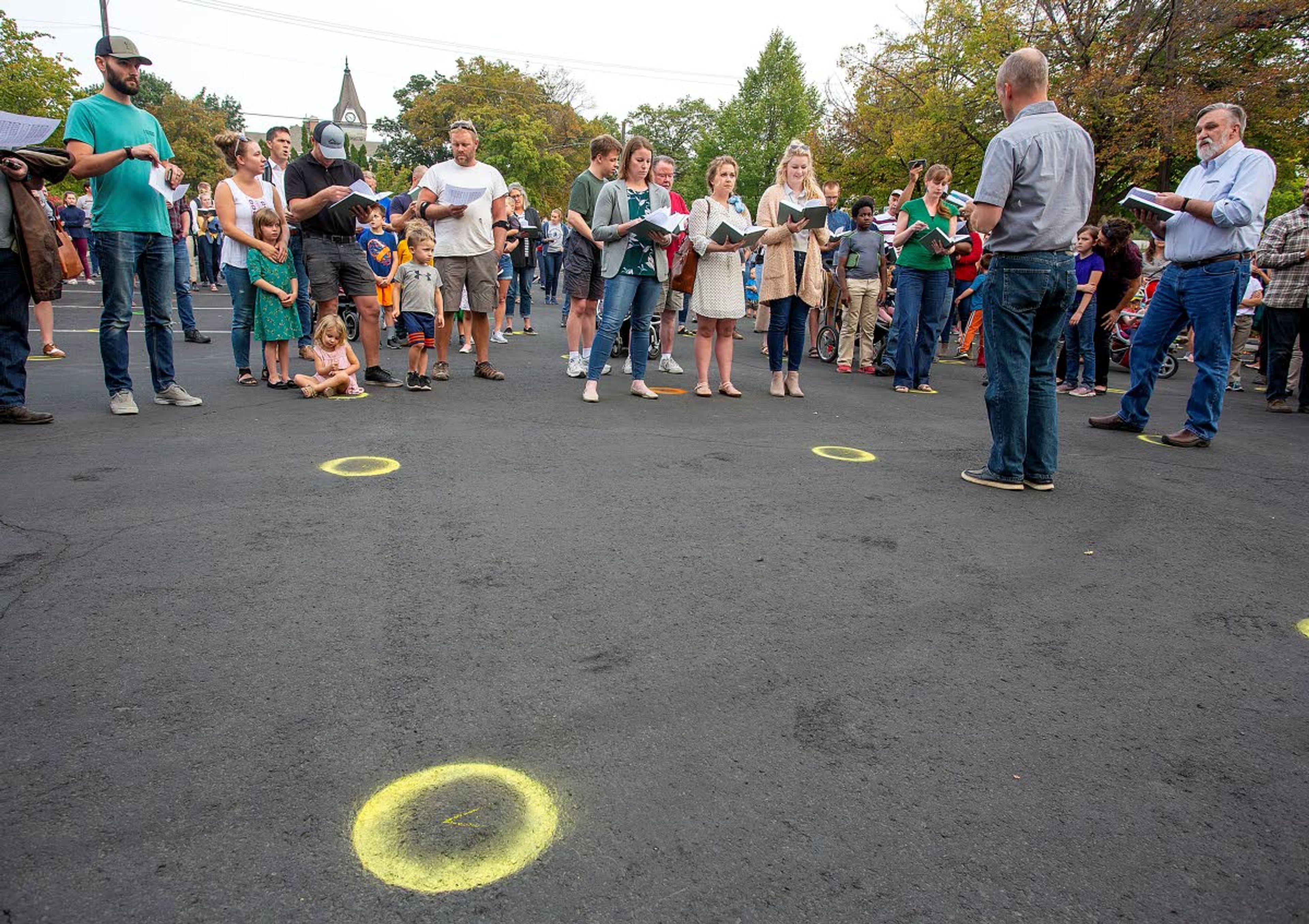 Christ Church Pastor Doug Wilson, right, sings with church members during a "flash psalm sing" organized by the church on Wednesday outside Moscow City Hall. City workers painted circles on the parking lot to indicate proper social distancing for people not wearing masks.