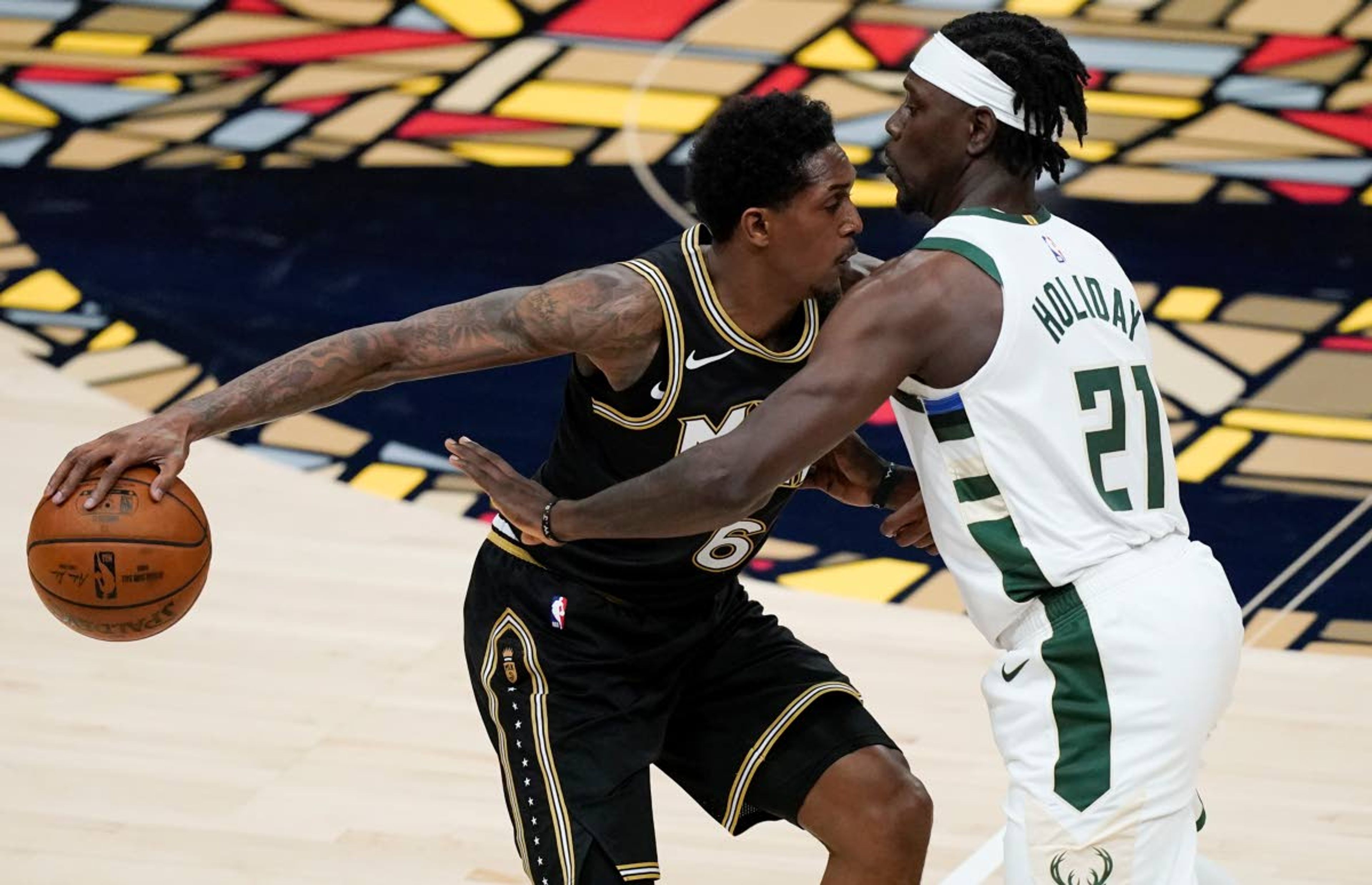 Hawks’ Lou Williams keeps the ball away from Bucks’ Jrue Holiday during the first half of Game 4 of the NBA Eastern Conference finals Tuesday in Atlanta.