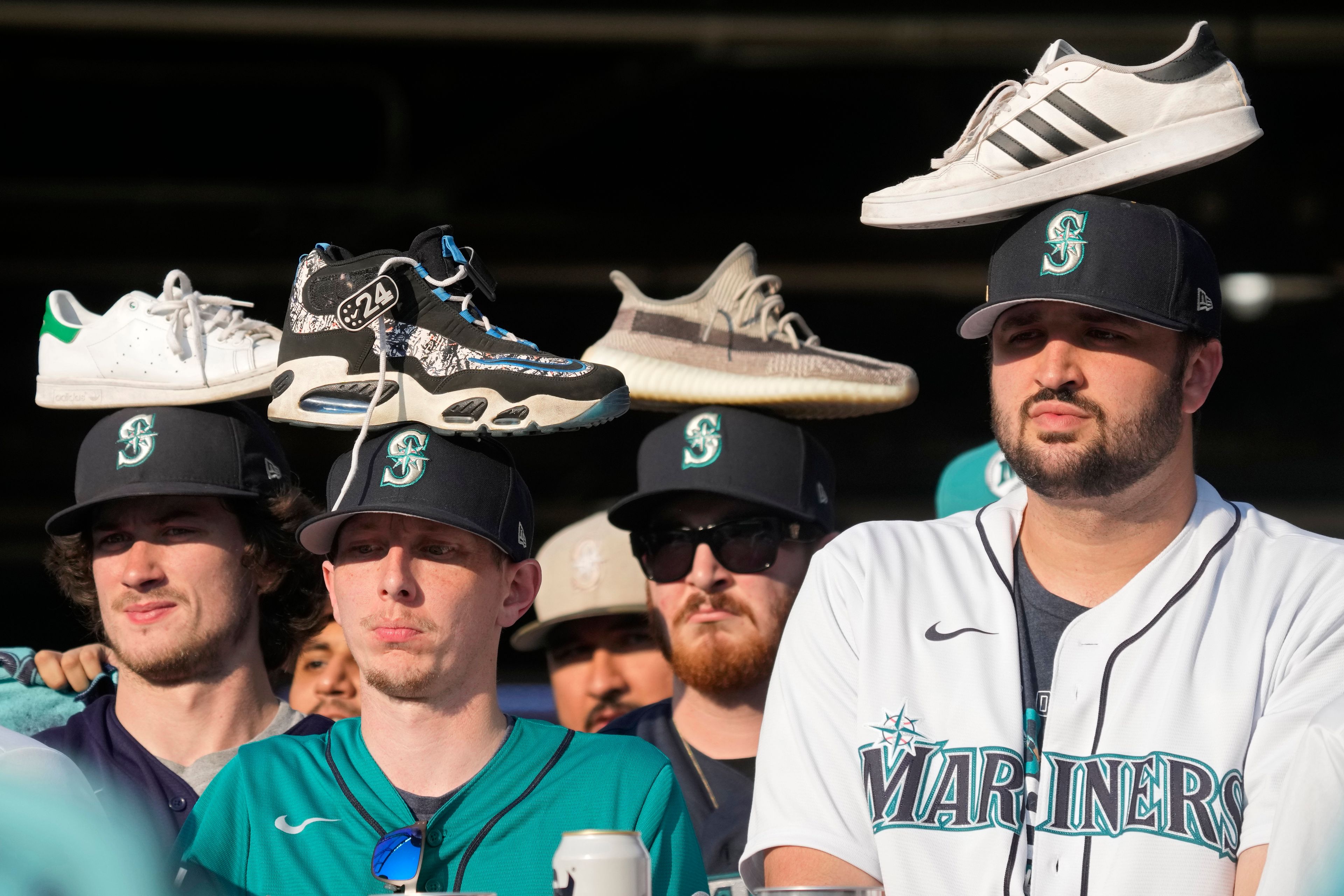 Seattle Mariners fans wear rally shoes on their heads during the eighth inning in Game 3 of an American League Division Series baseball game between the Seattle Mariners and the Houston Astros, Saturday, Oct. 15, 2022, in Seattle. (AP Photo/Stephen Brashear)