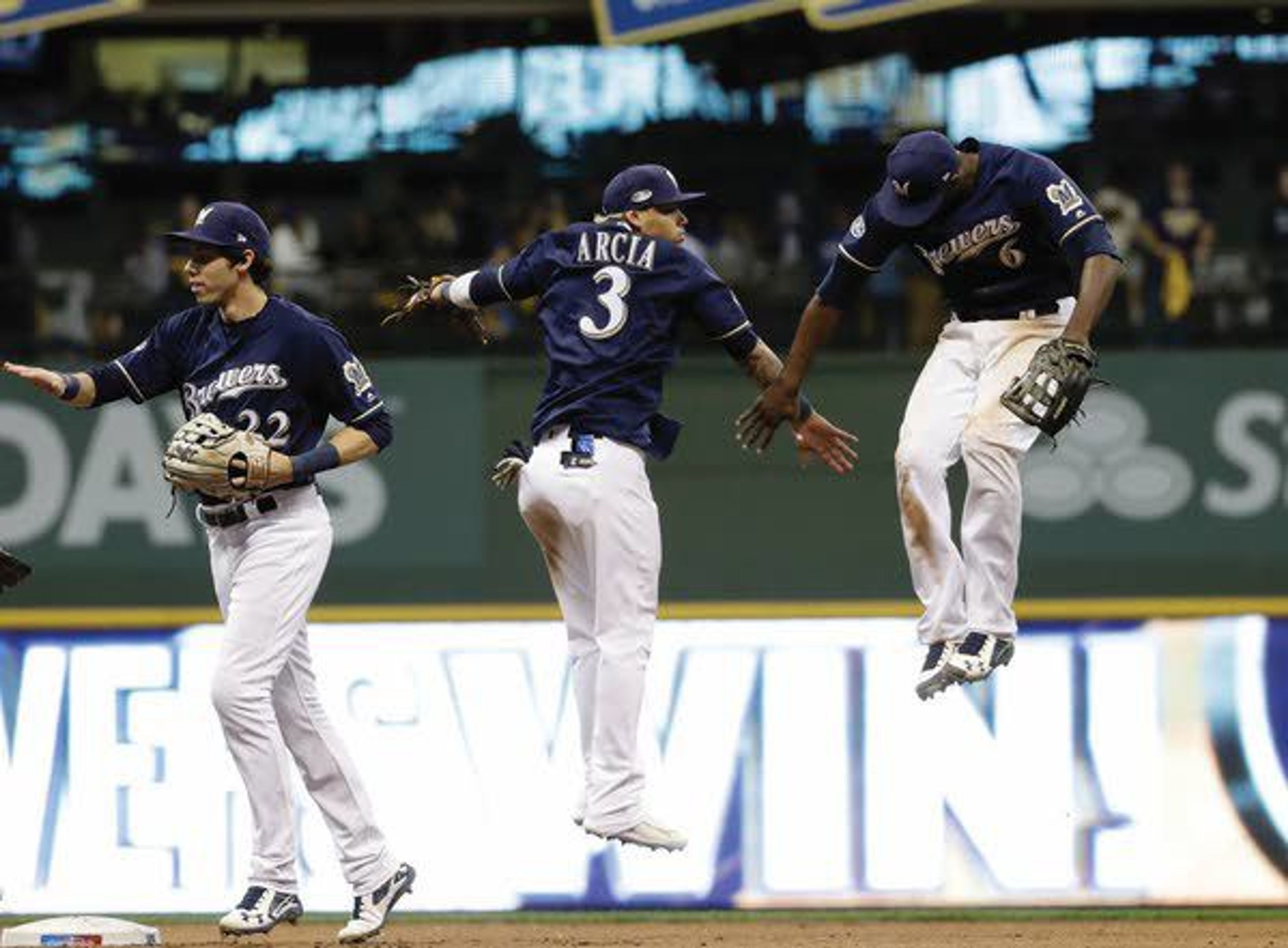 Brewers’ Lorenzo Cain, Orlando Arcia and Christian Yelich celebrate after Game 1 of the National League Championship Series game Friday in Milwaukee.