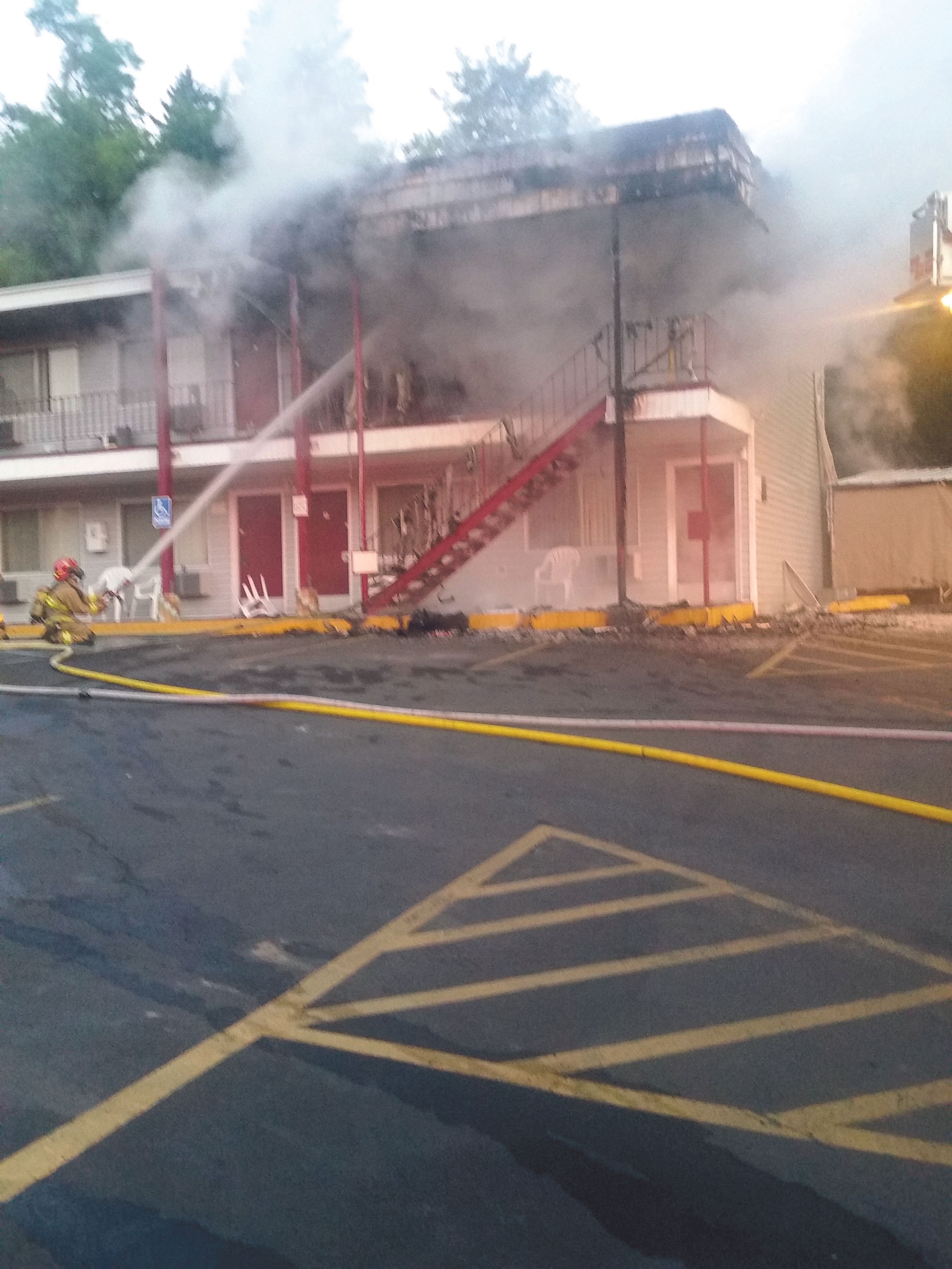 A firefighter directs a stream of water onto the burning ceiling of Room 59 at the American Travel Inn on Grand Avenue in Pullman Tuesday morning.