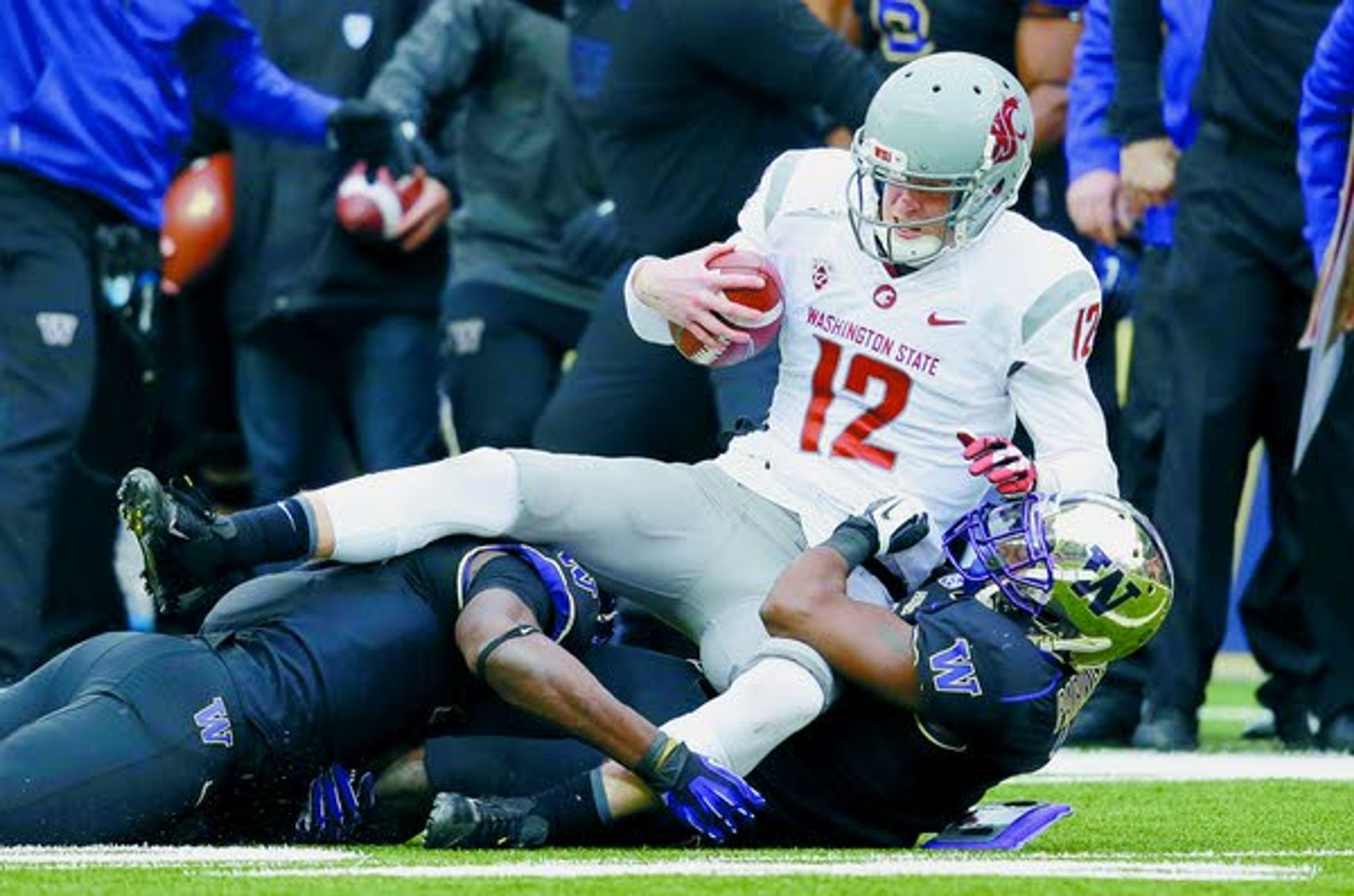 Washington State quarterback Connor Halliday (12) is pulled down on a keeper by a pair of Washington defenders in the second half Friday in Seattle. Washington won the annual Apple Cup, 27-17.